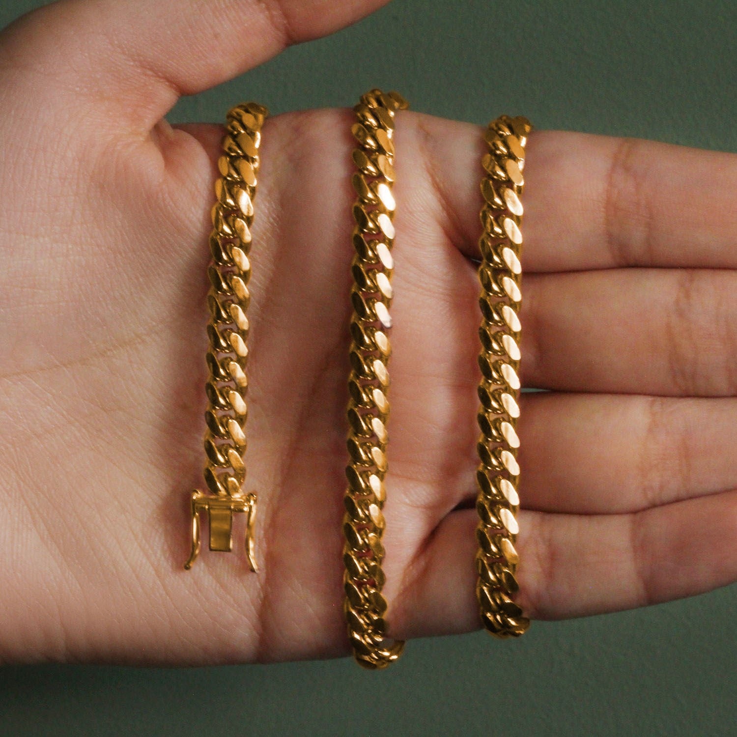 14k yellow gold classic Miami Cuban solid chain with a box clasp on a hand.