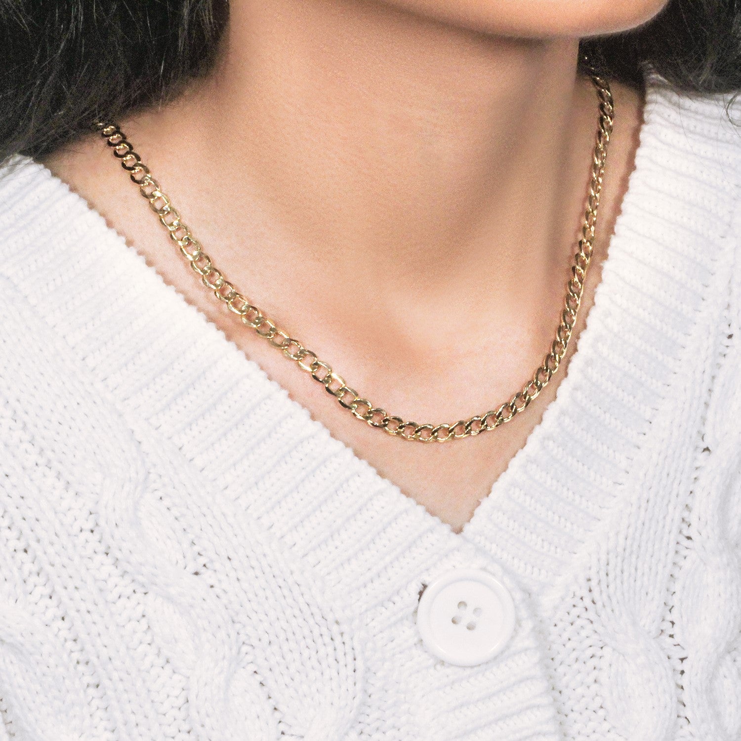 10k yellow gold curb chain on a person wearing a white cable-knit sweater.
