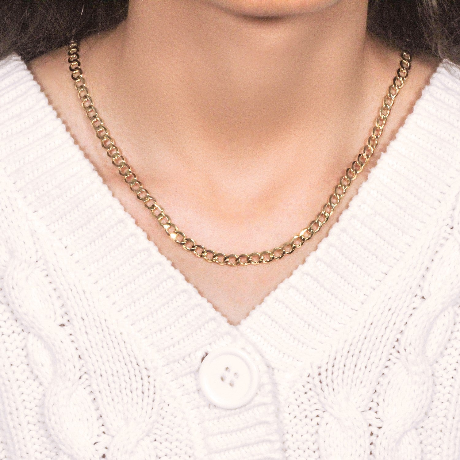 10k yellow gold curb chain on a person wearing a white cable knit sweater.