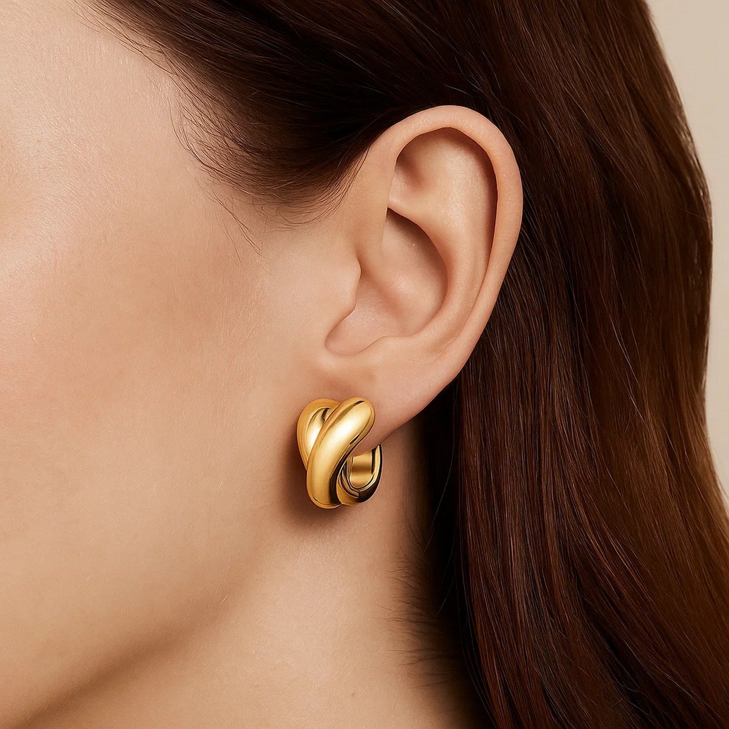 Crossover hoop earrings in 14K yellow gold on a model's ear.