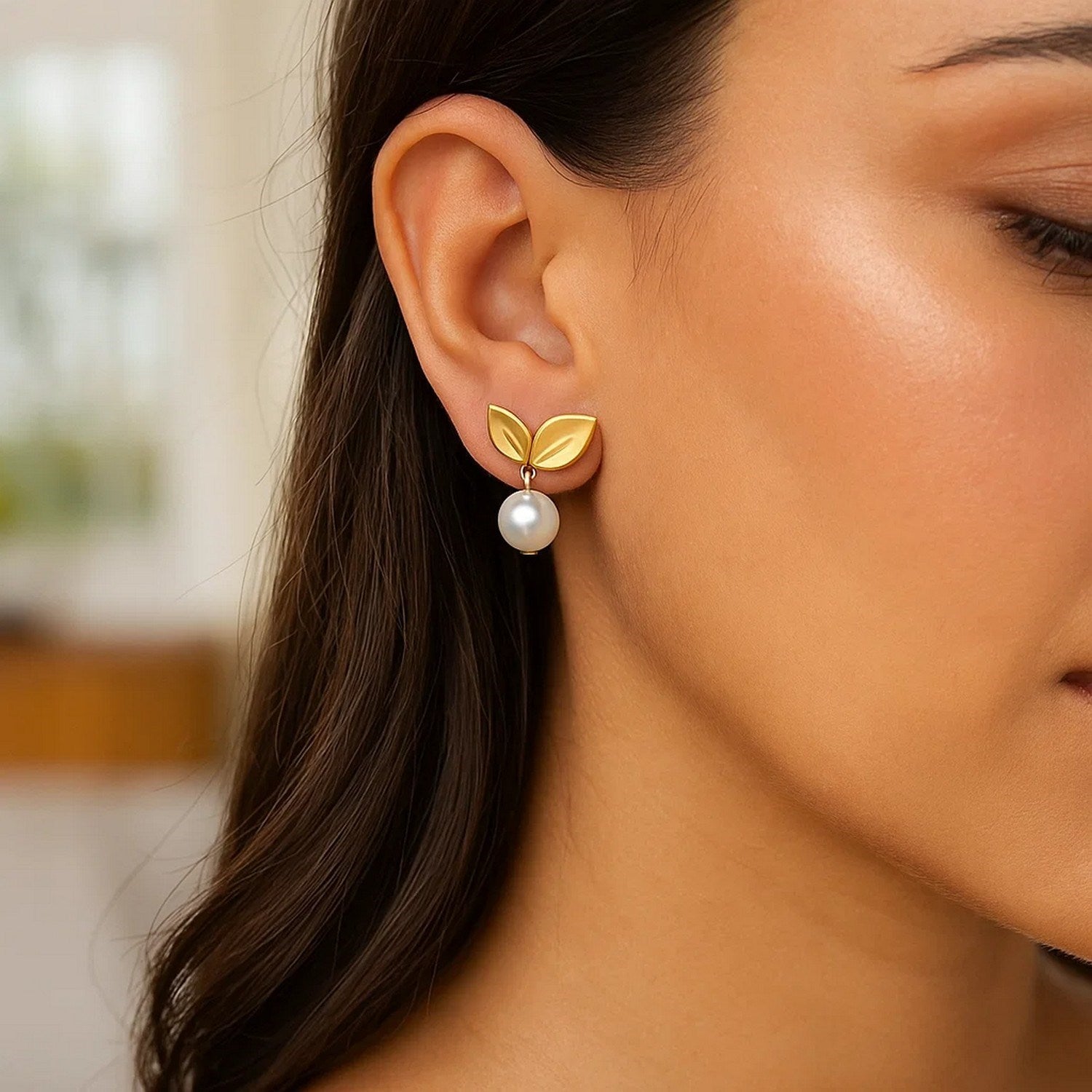 14K yellow gold cherry leaf pearl drop earrings on a woman's ear.