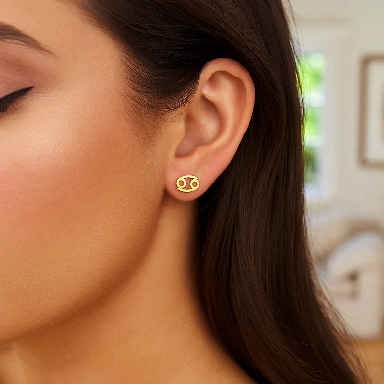 14k yellow gold Cancer stud earring on a woman's ear.