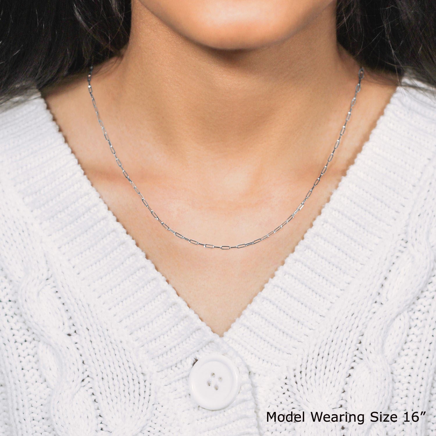 A 14k white gold adjustable paperclip chain is worn around a person's neck.