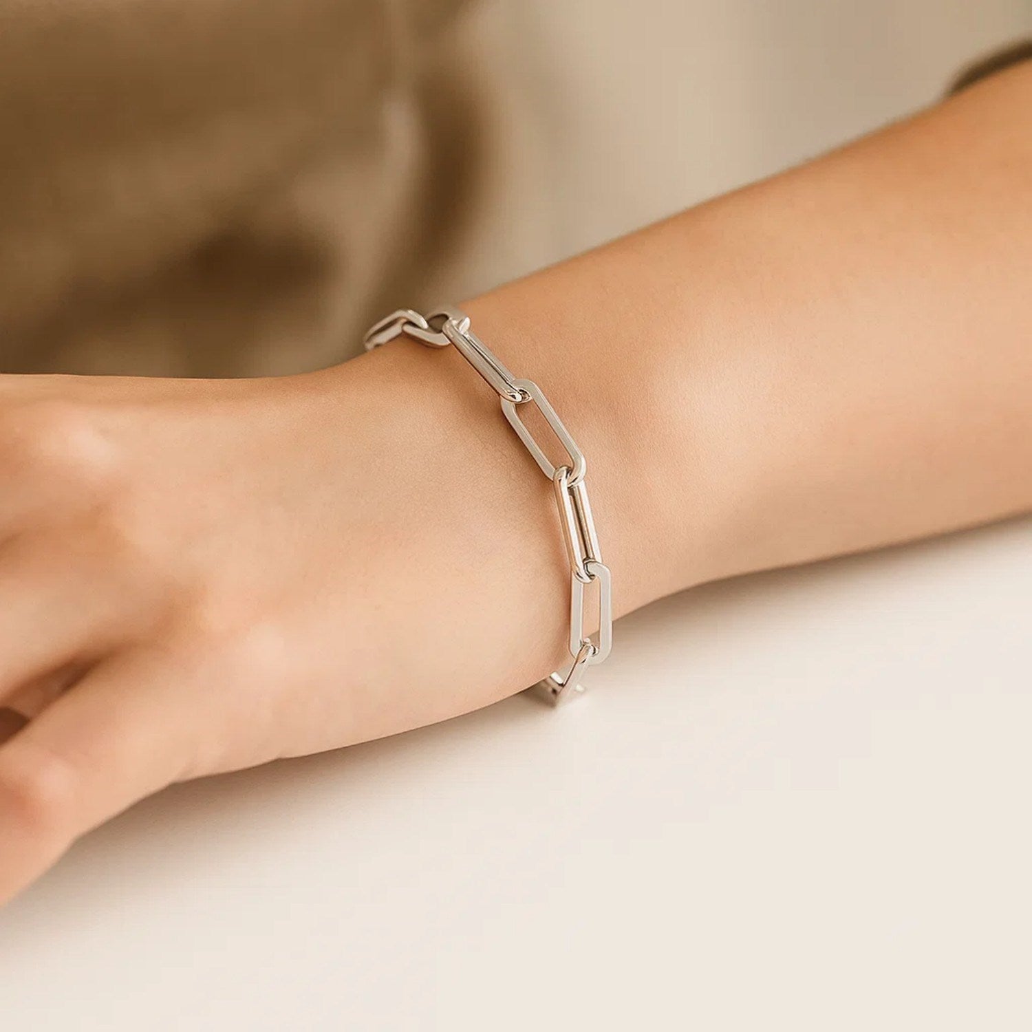 14K white gold extra wide paperclip chain bracelet on a person's wrist.