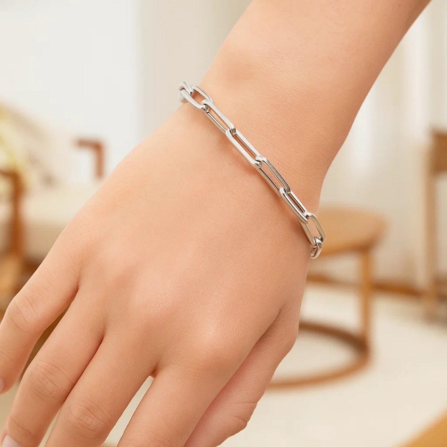 14K white gold extra wide paperclip chain bracelet on a person's wrist.