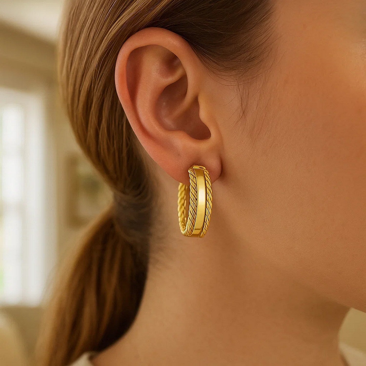 14K yellow gold triple row hoop earrings on a woman's ear.