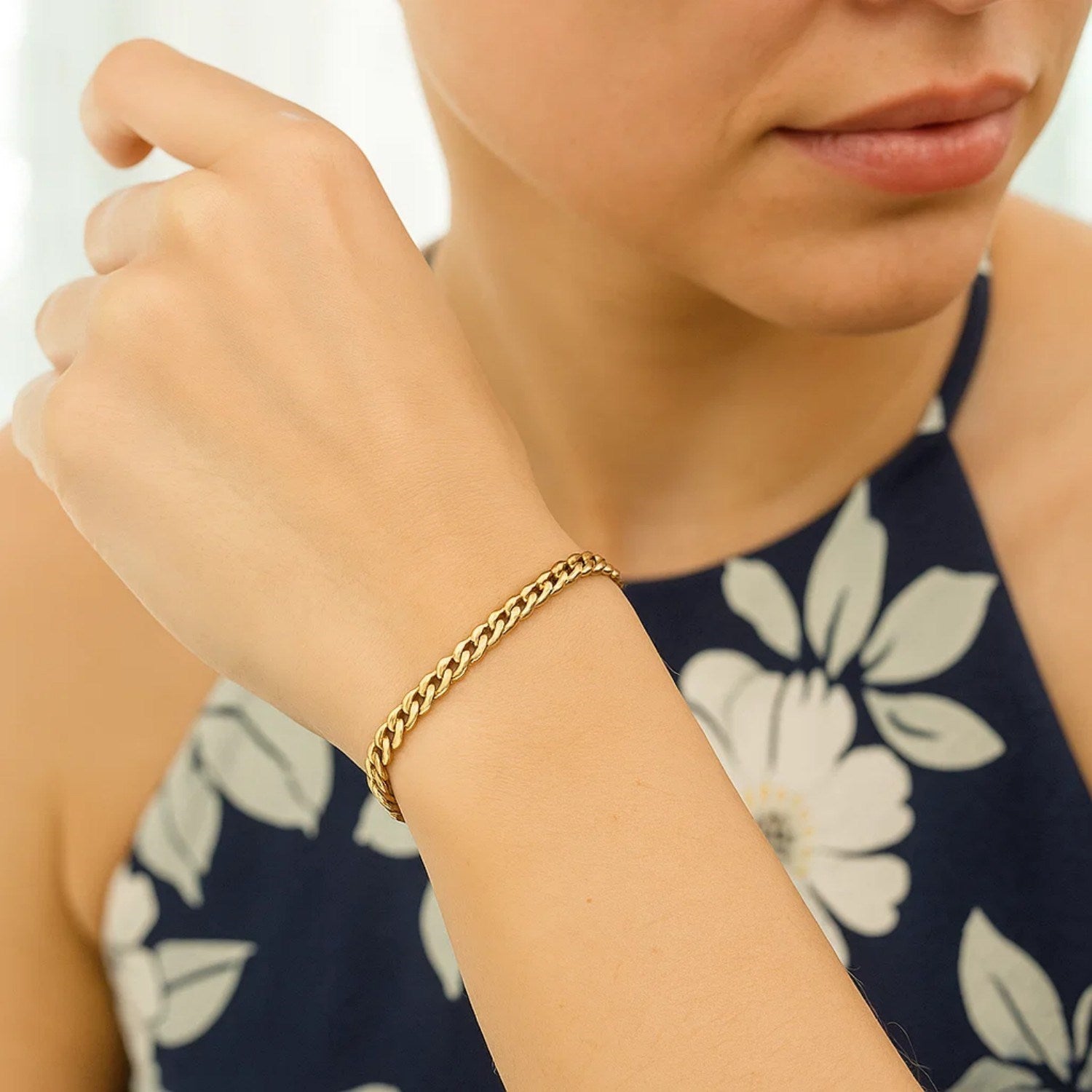 A woman wears a 14k yellow gold classic Miami Cuban solid bracelet.