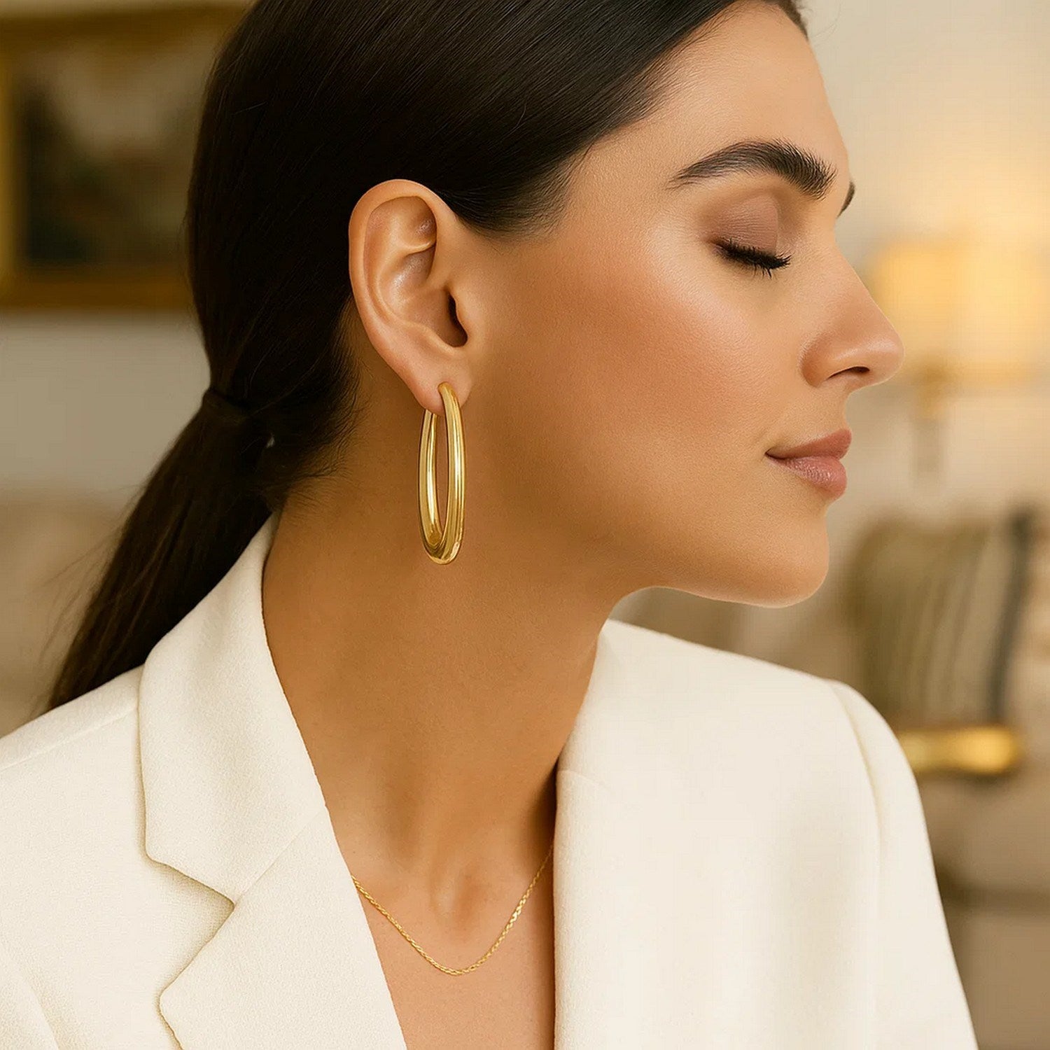 14k yellow gold elongated oval hoop earrings on a woman.
