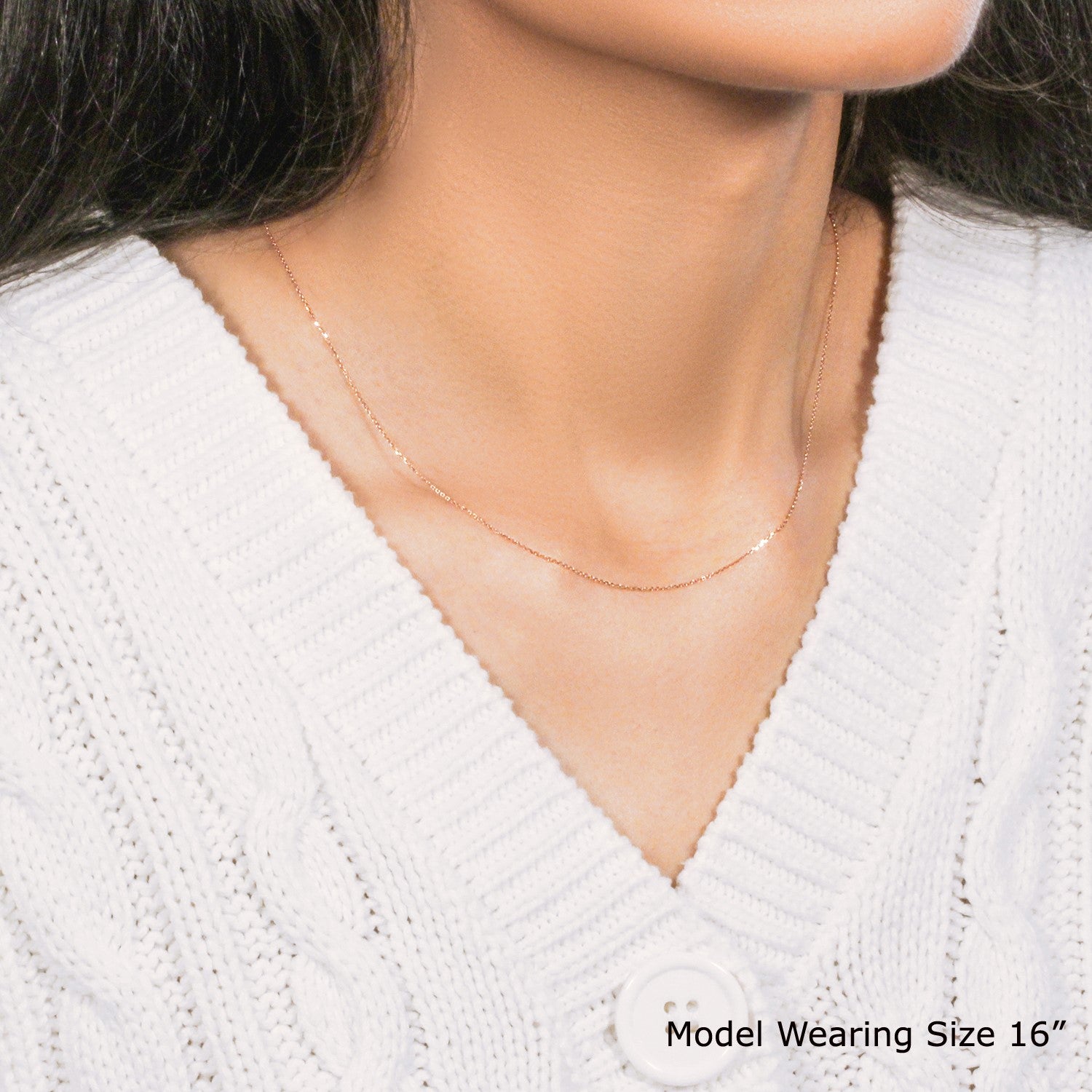 A 14k rose gold diamond cut cable link chain on a model wearing a white sweater.