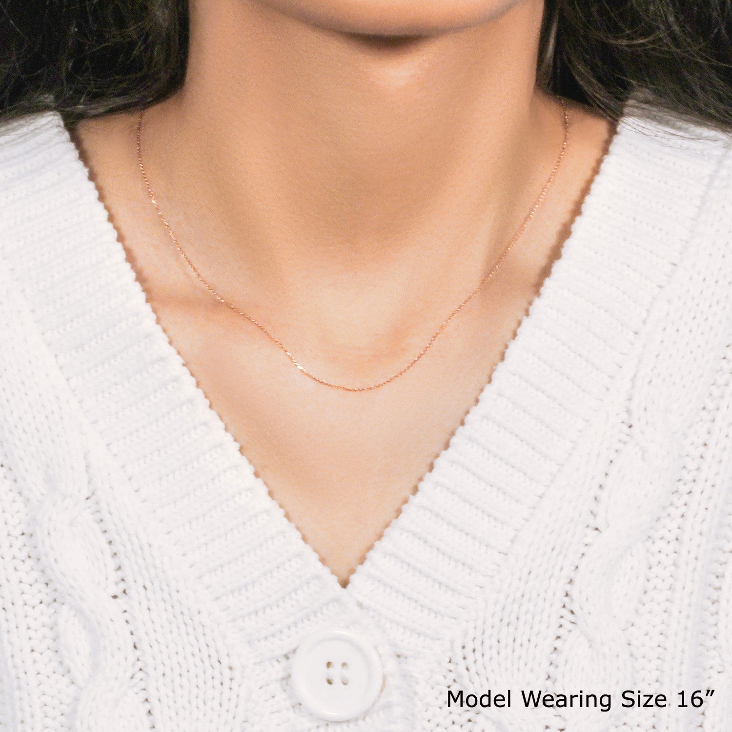 A 14k rose gold diamond cut cable link chain on a model wearing a white sweater.