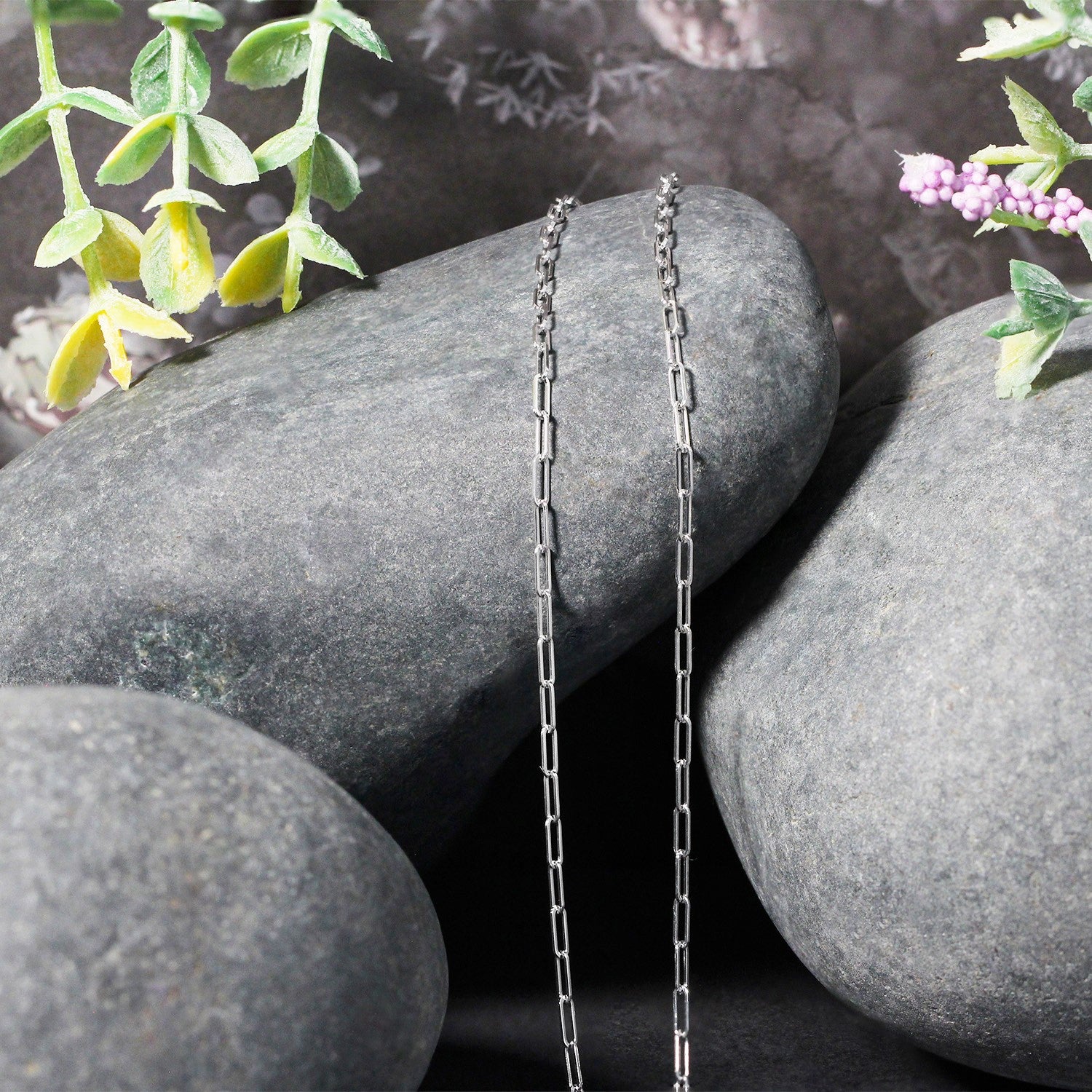 14K white gold paperclip chain with 1.50 mm links draped over gray stones.