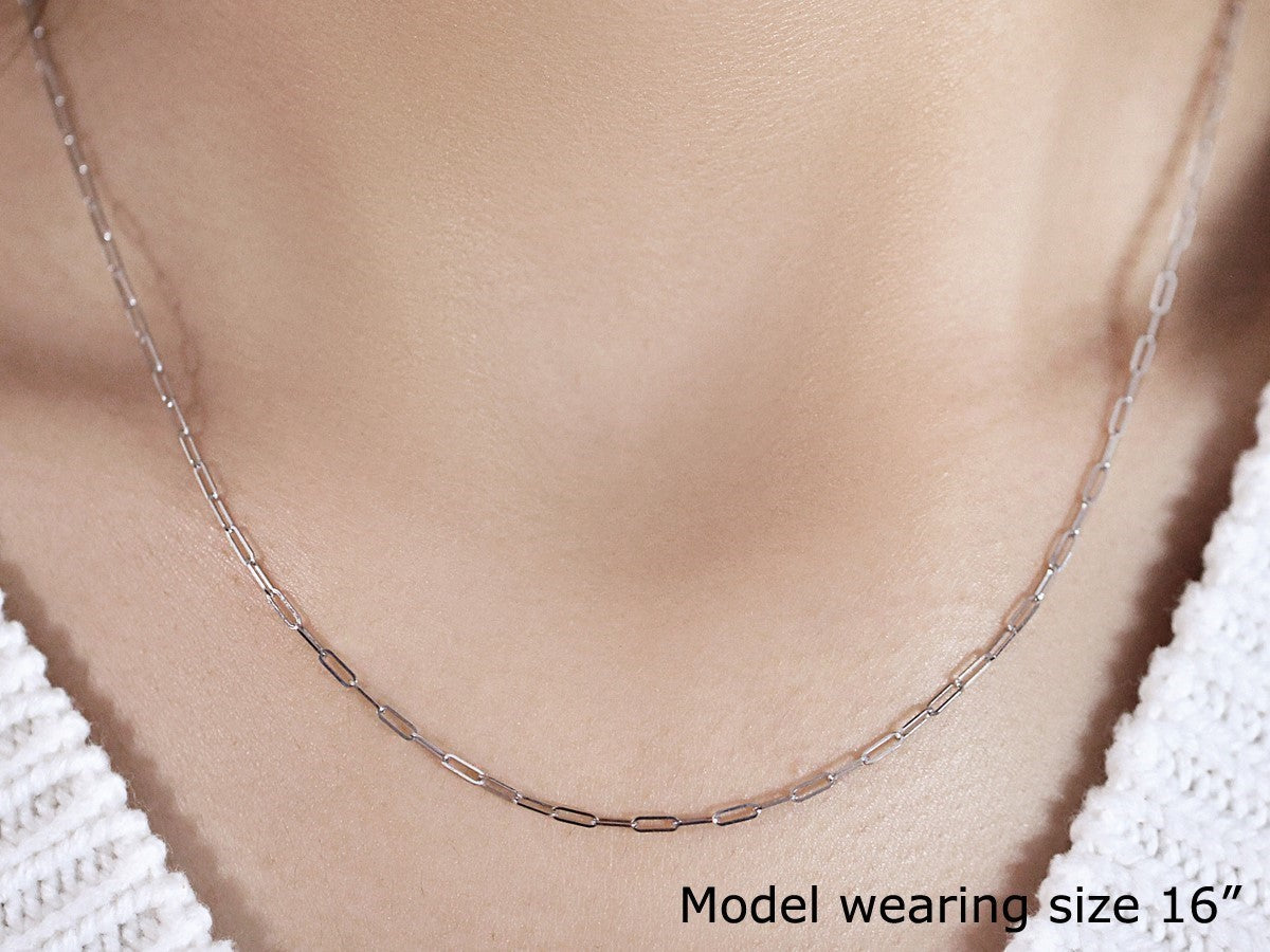 A 14K white gold 1.5mm paperclip chain necklace is worn by a model.
