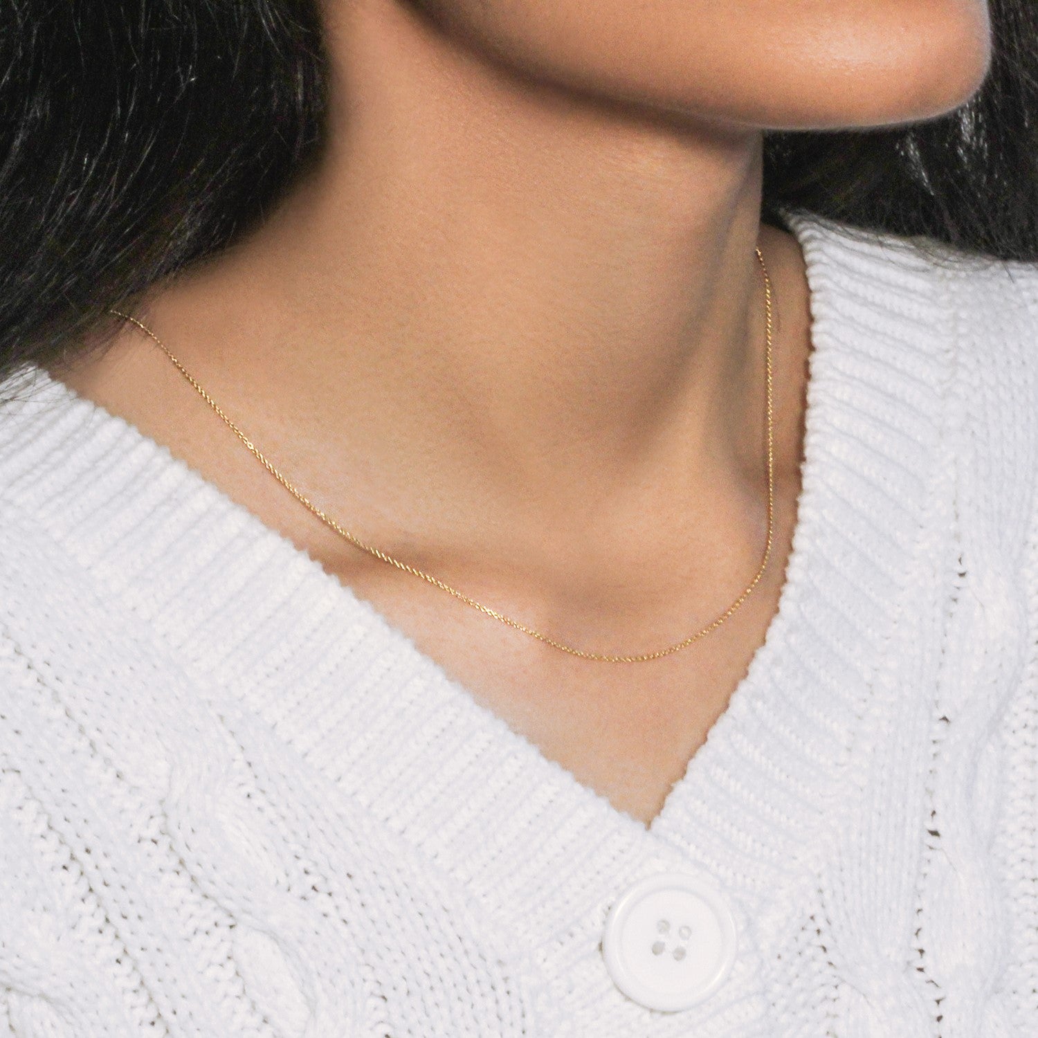 14k yellow gold oval cable link chain on a person wearing a white sweater.