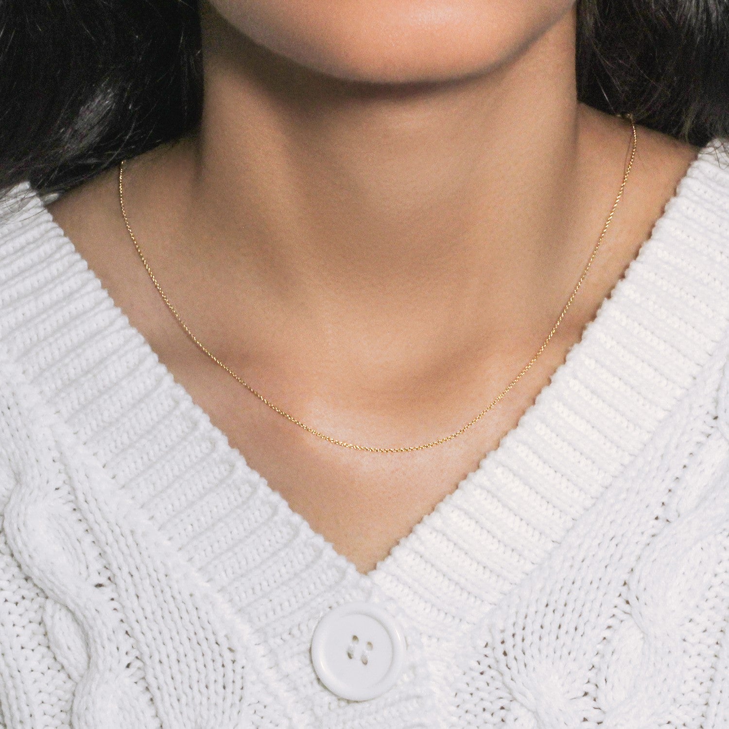 14k yellow gold oval cable link chain on a person wearing a white cable-knit sweater.