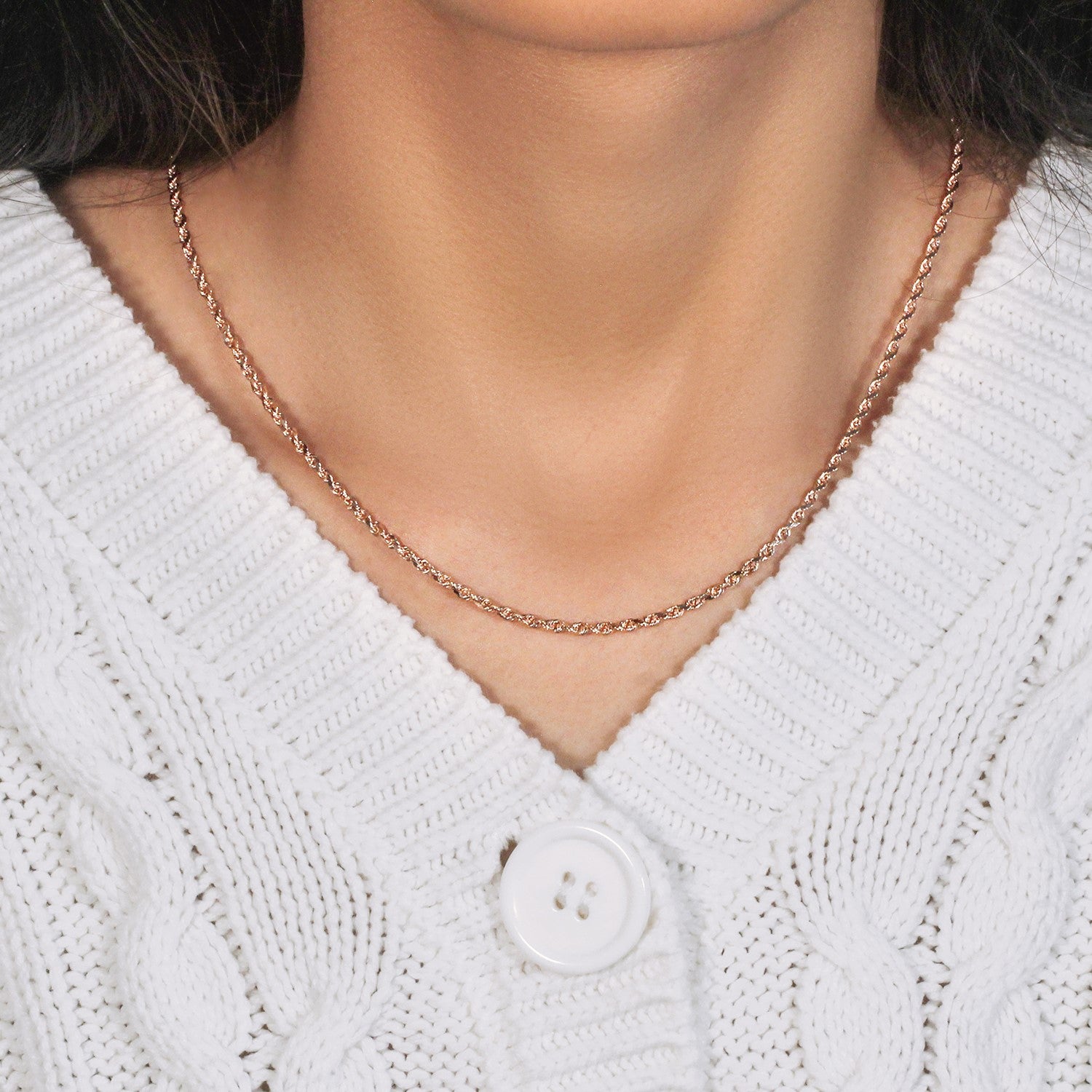 14k rose gold solid diamond cut rope chain on a person wearing a white cable-knit sweater.