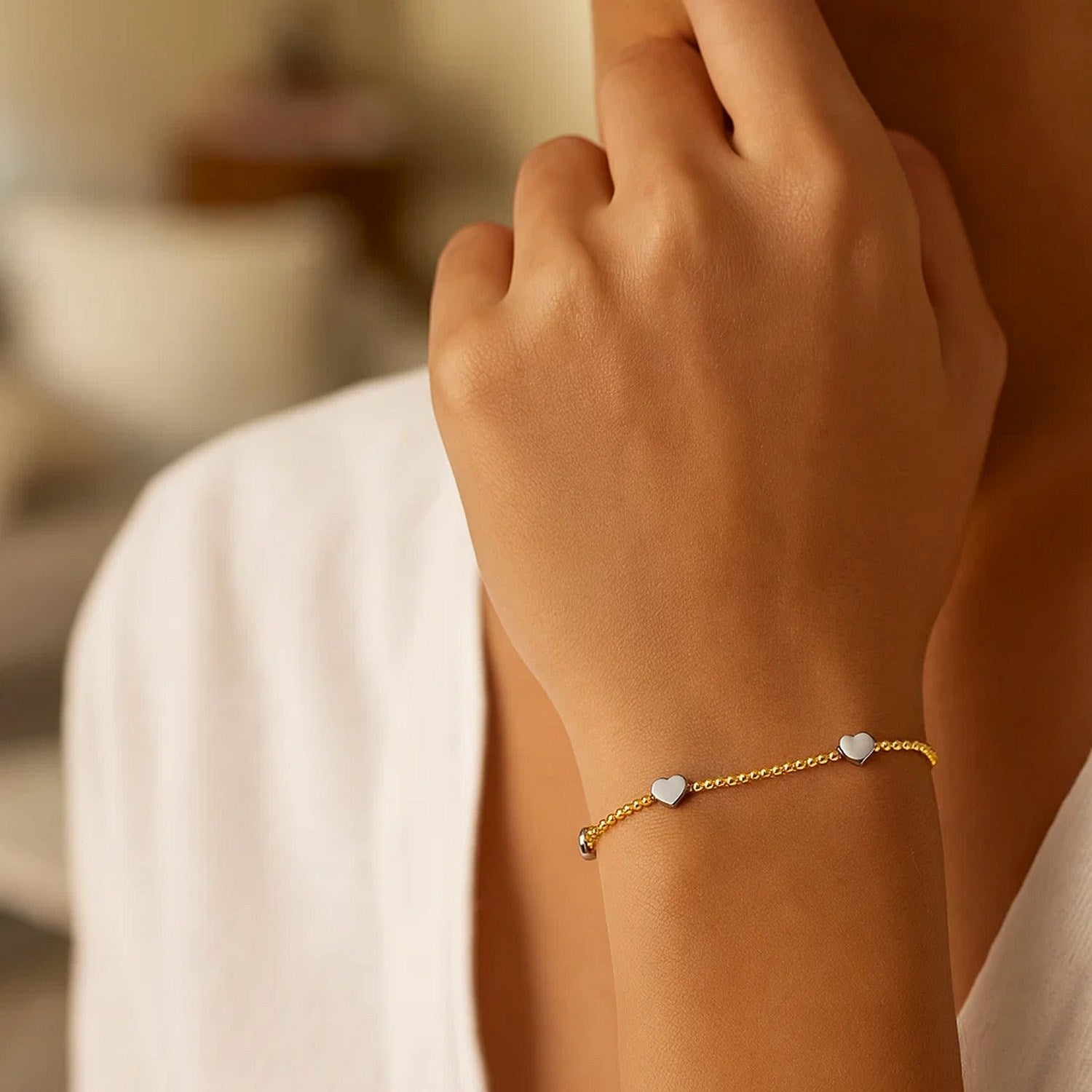 A 14K yellow and white gold heart bead bracelet on a person's arm.