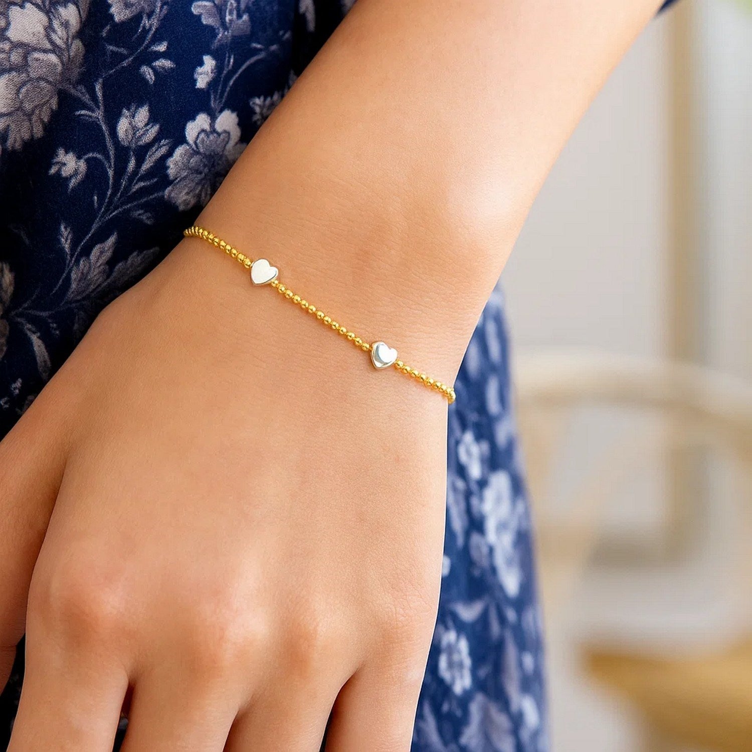 A 14K yellow and white gold heart bead bracelet on a person's wrist.