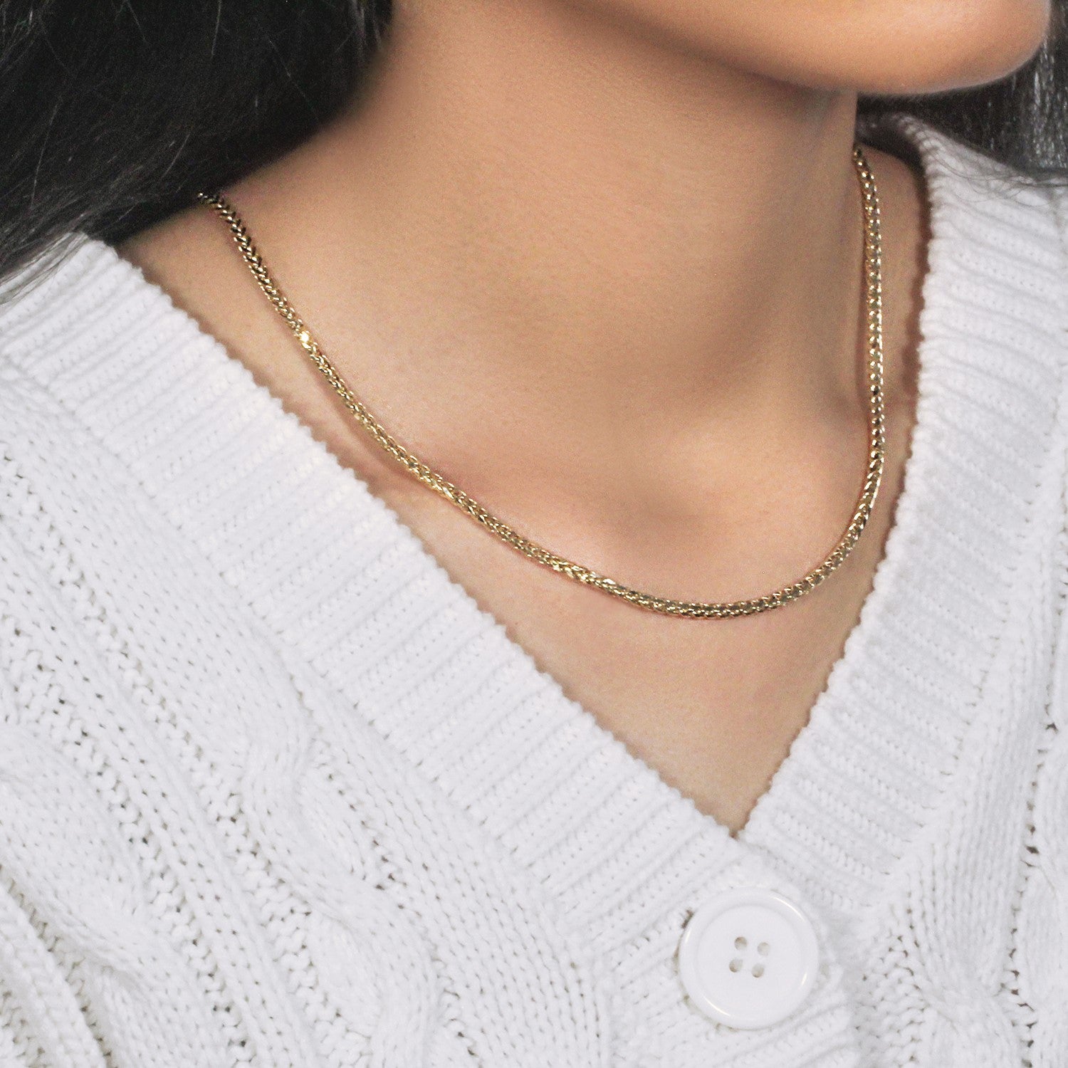 A 14k yellow gold diamond-cut round Franco chain is worn around a person's neck.