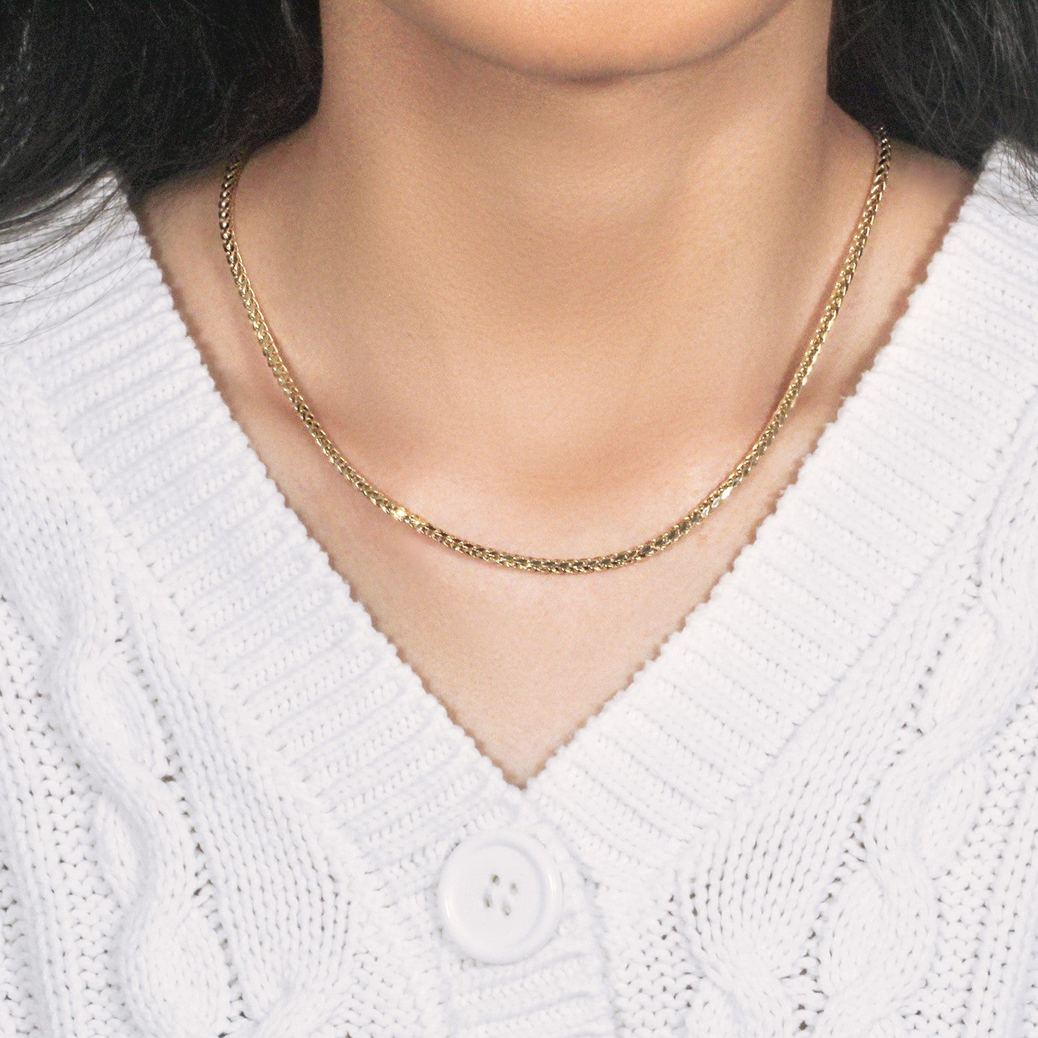 A 14k yellow gold diamond-cut round Franco chain is worn around a person's neck.