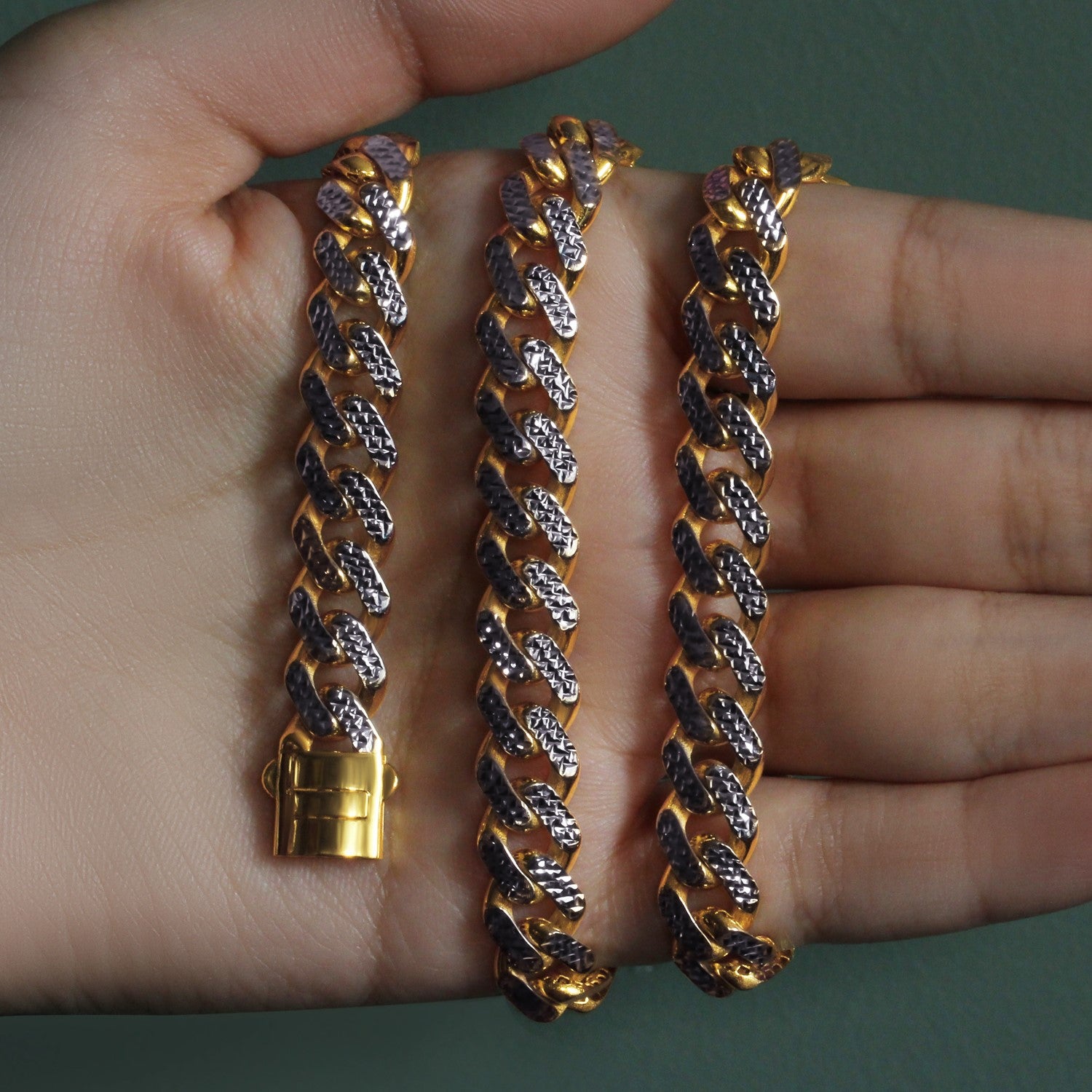 A two-tone gold Miami Cuban chain necklace with white pave, held in a hand.