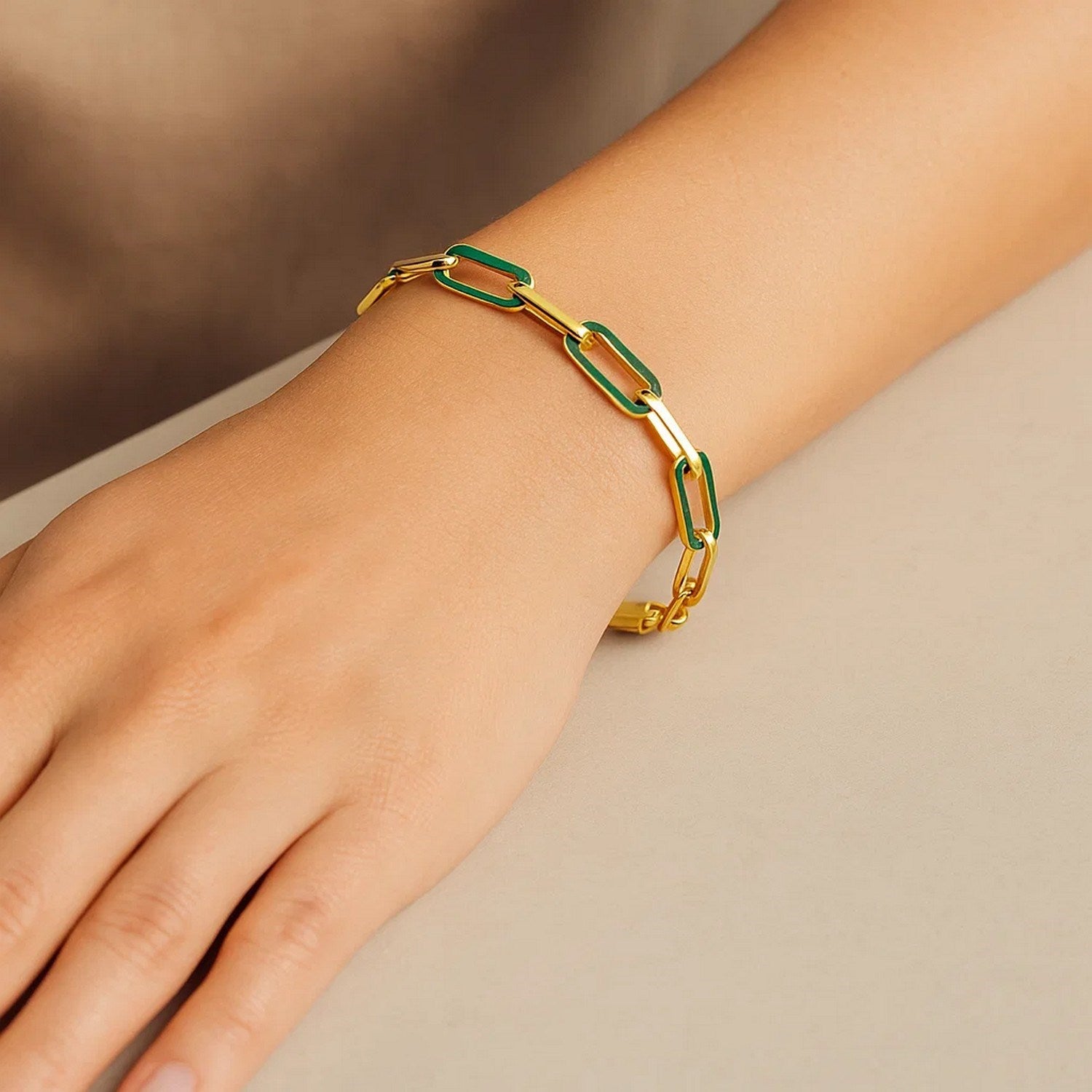 A 14k yellow gold paperclip link bracelet with green malachite on a person's wrist.