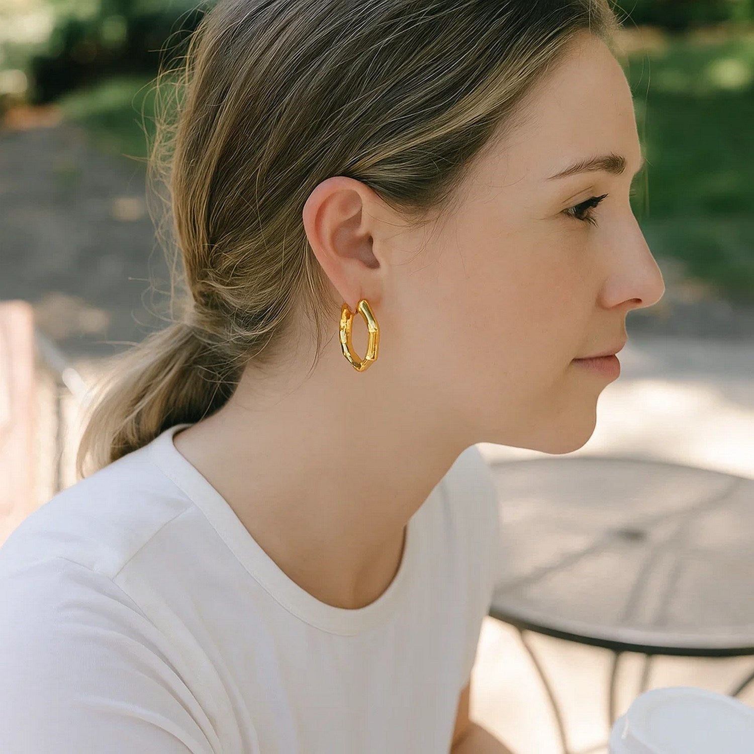 14k yellow gold medium bamboo hoop earrings on a woman.