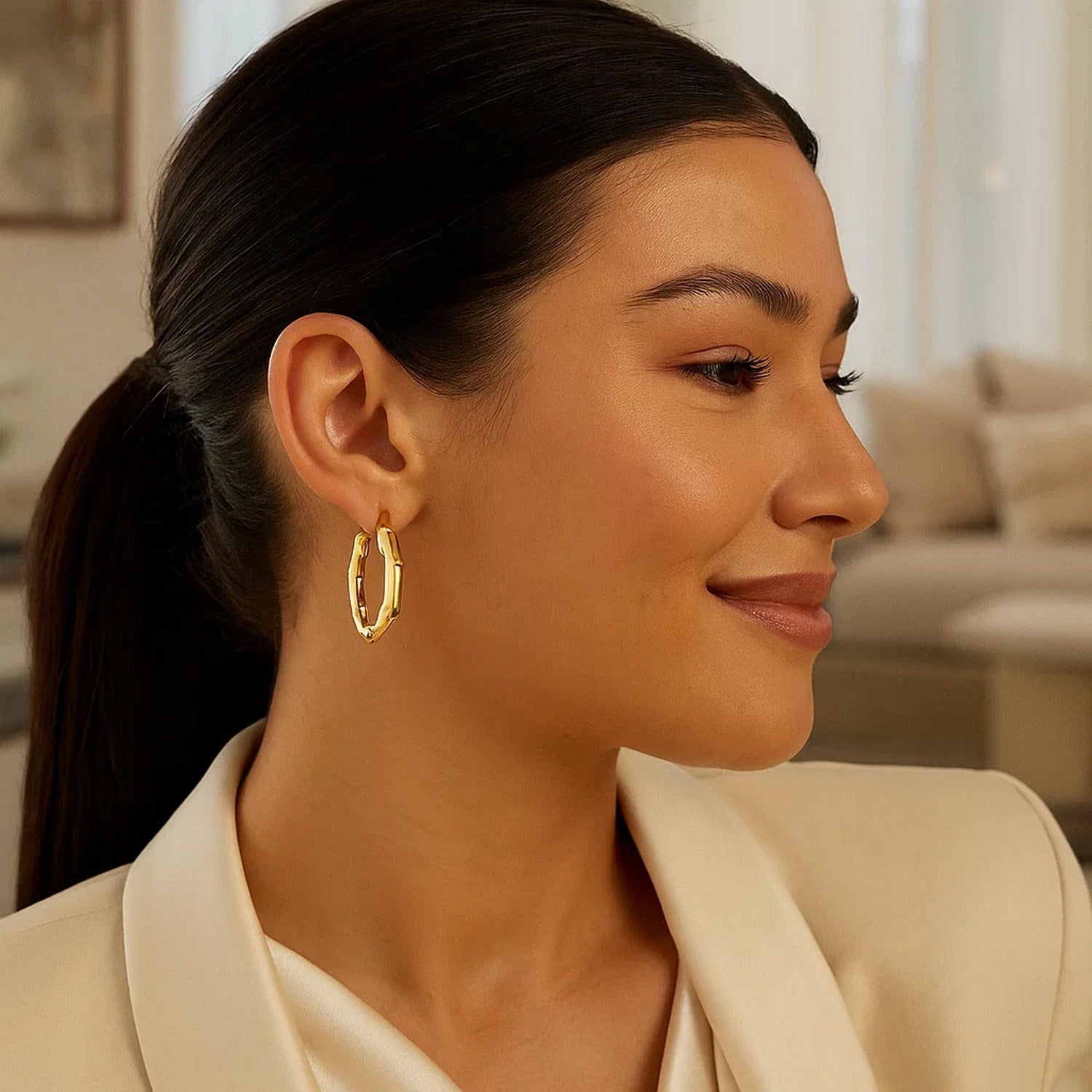 14k yellow gold medium bamboo hoop earrings on a woman's ear.