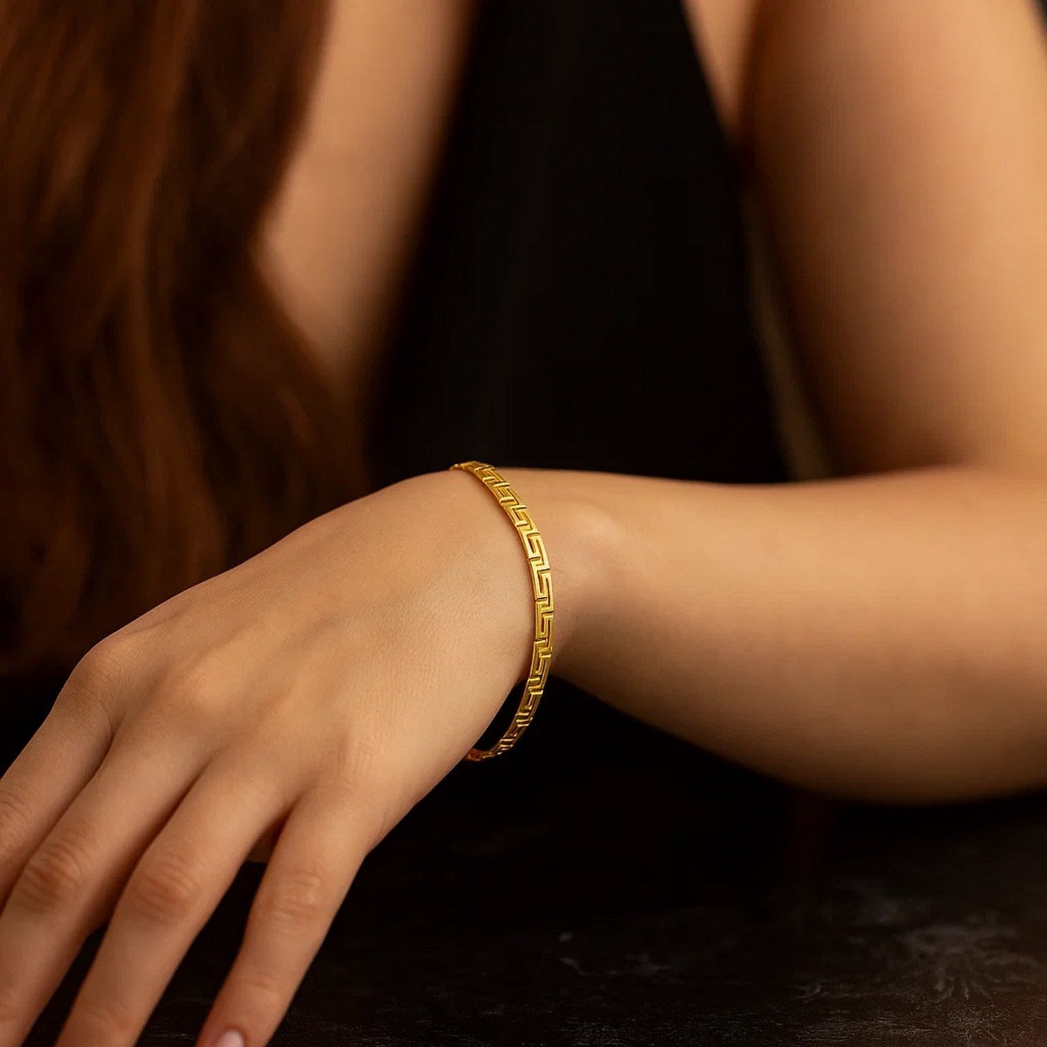14k yellow gold Greek fret design fancy bracelet on a woman's wrist.