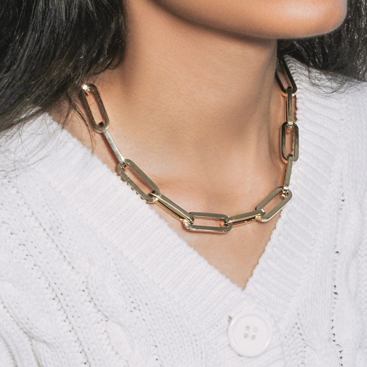 14k yellow gold extra wide paperclip chain necklace on a person wearing a white sweater.