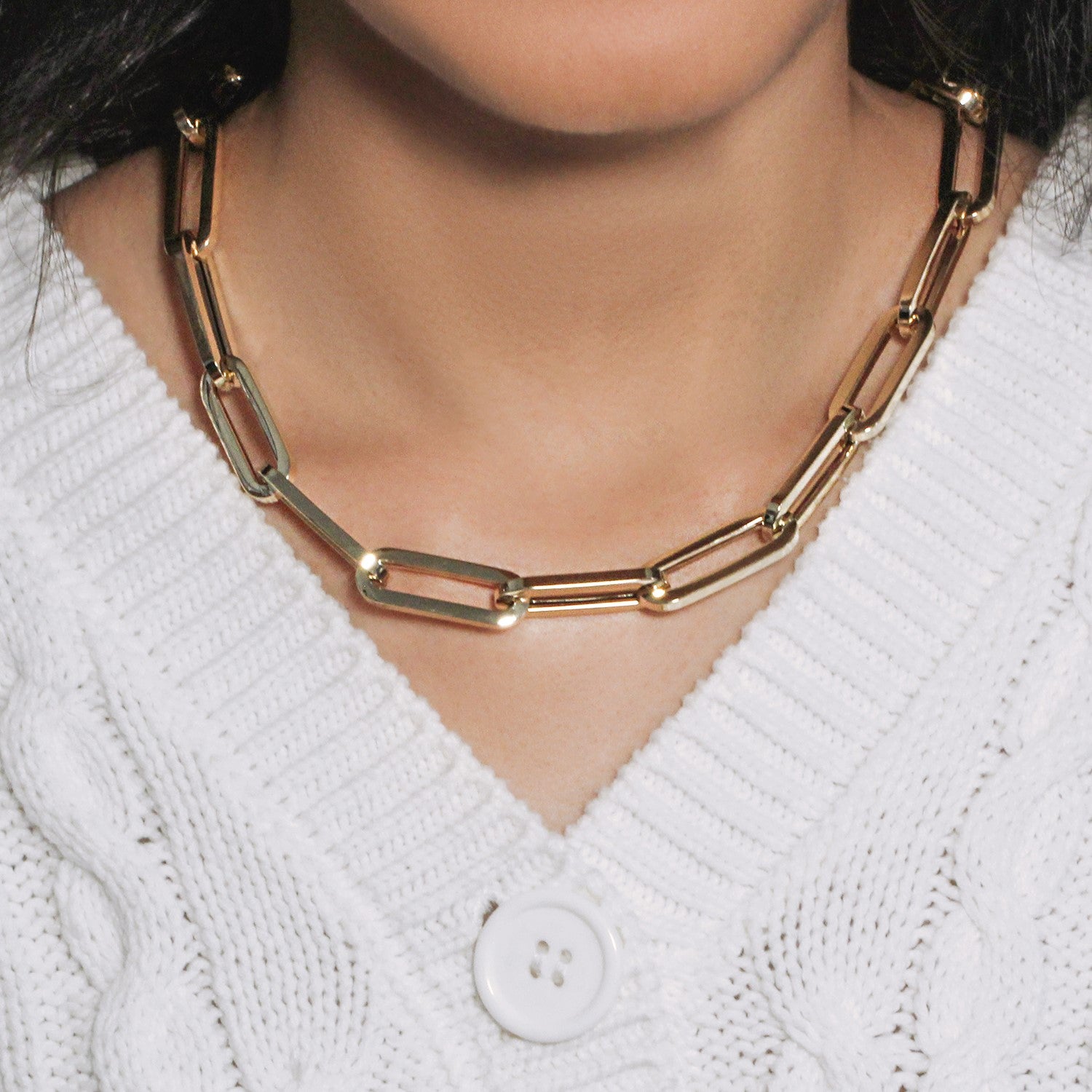 14k yellow gold extra wide paperclip chain necklace on a person wearing a white sweater.