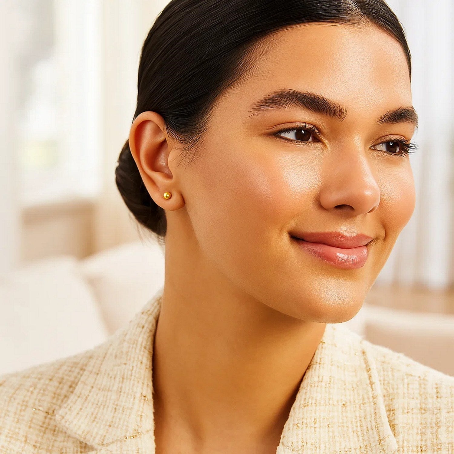 10k yellow gold ball style stud earrings on a woman's ear.