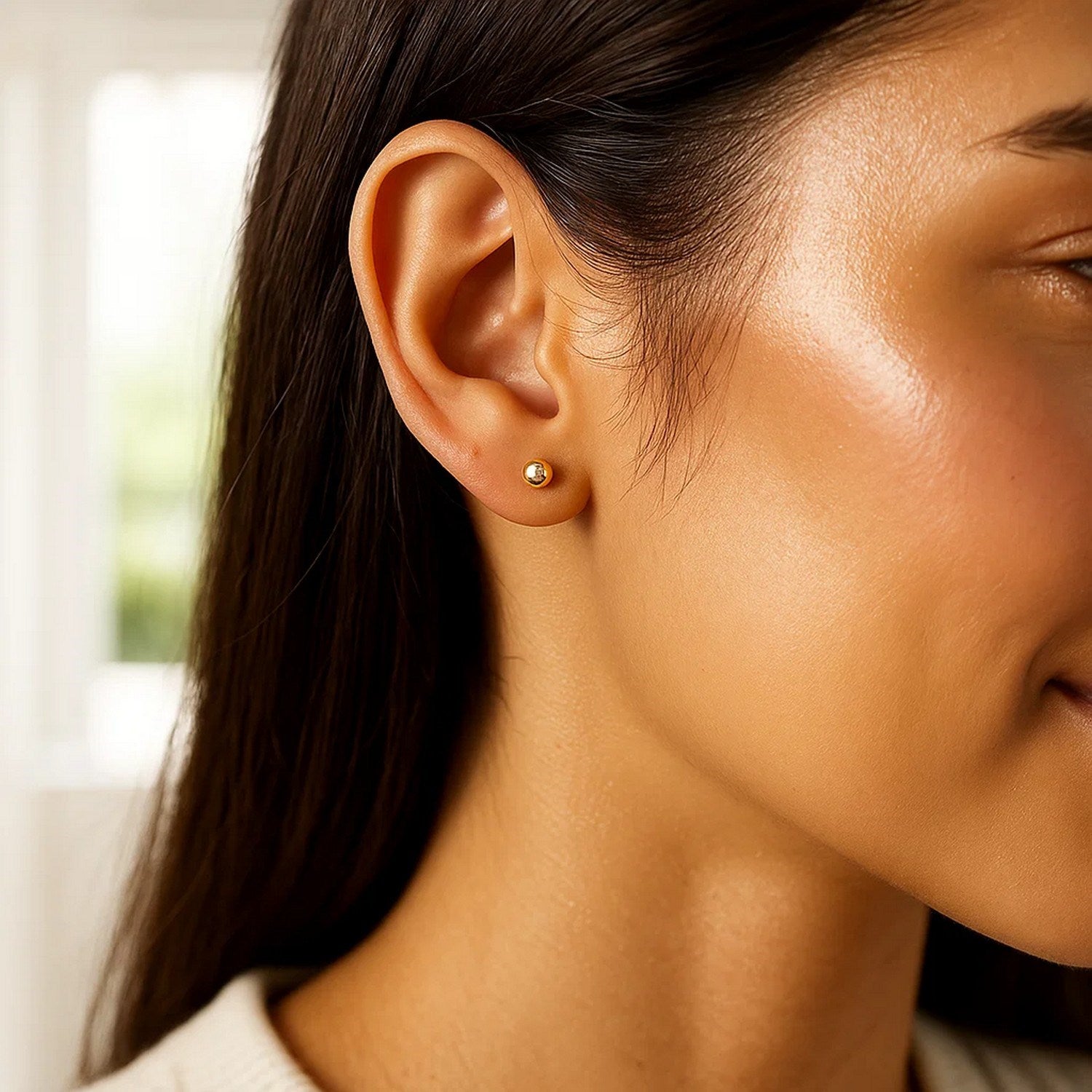 10k yellow gold ball stud earring on a woman's ear.