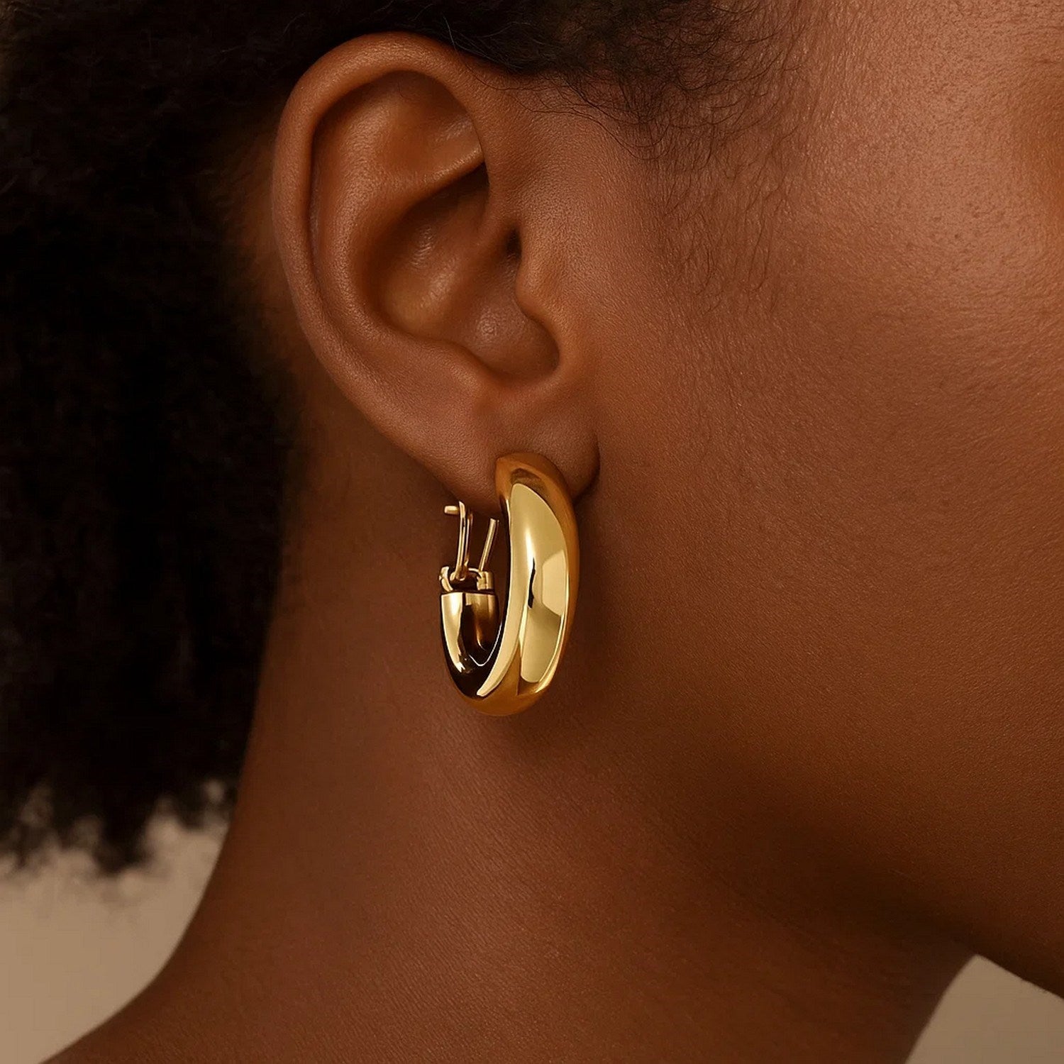 14k yellow gold large omega C hoops with a high polish finish.