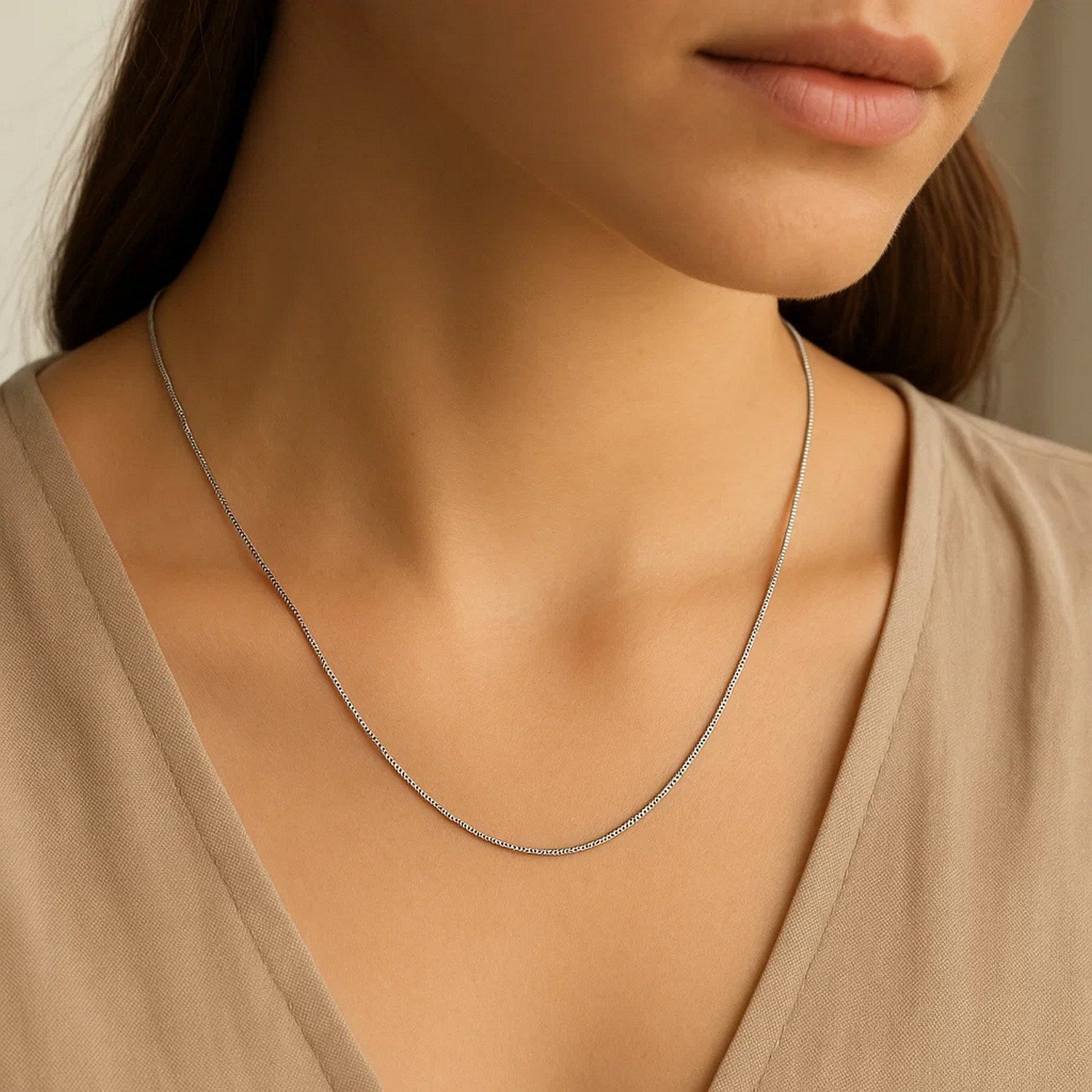 A thin 14k white gold box chain is worn around a person's neck.