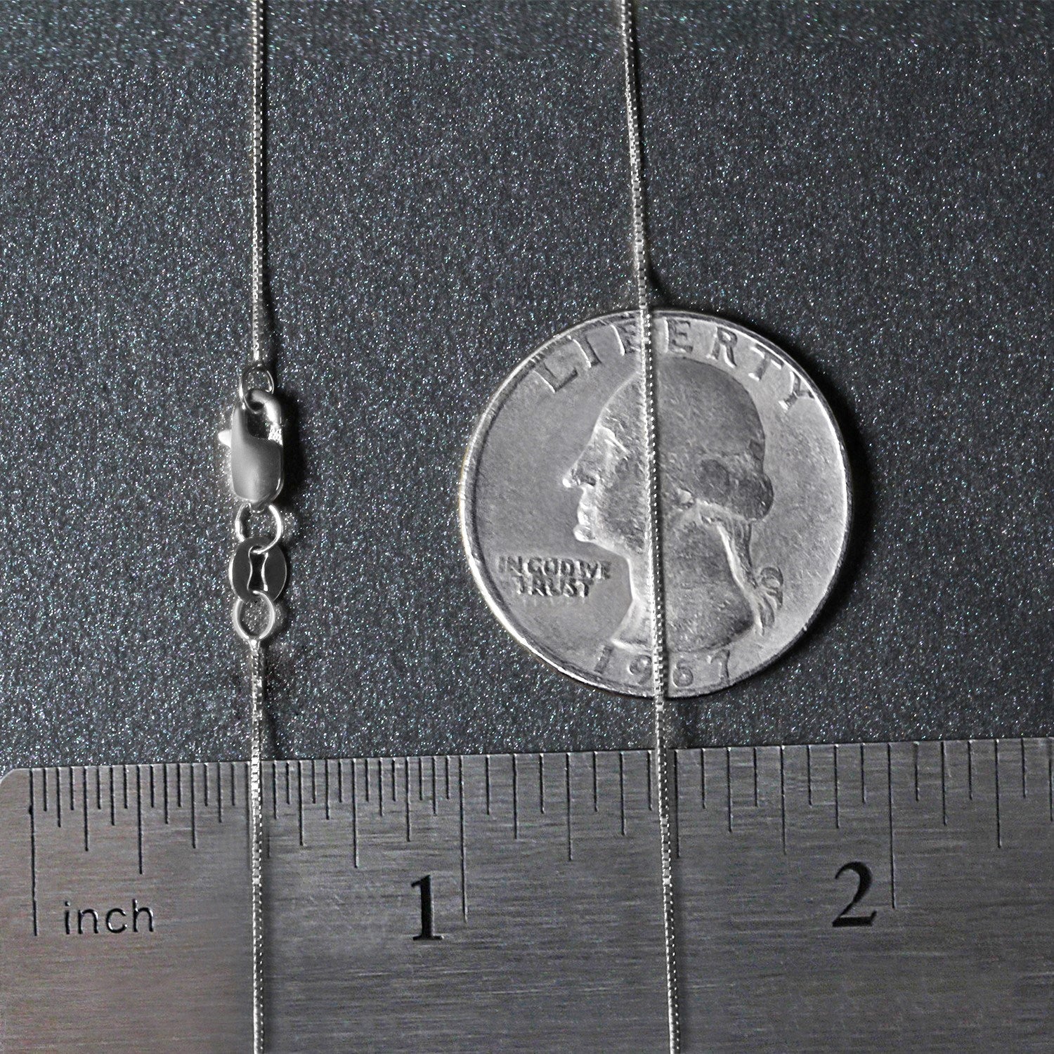A 14k white gold classic box chain with a lobster clasp, measured against a ruler and coin.