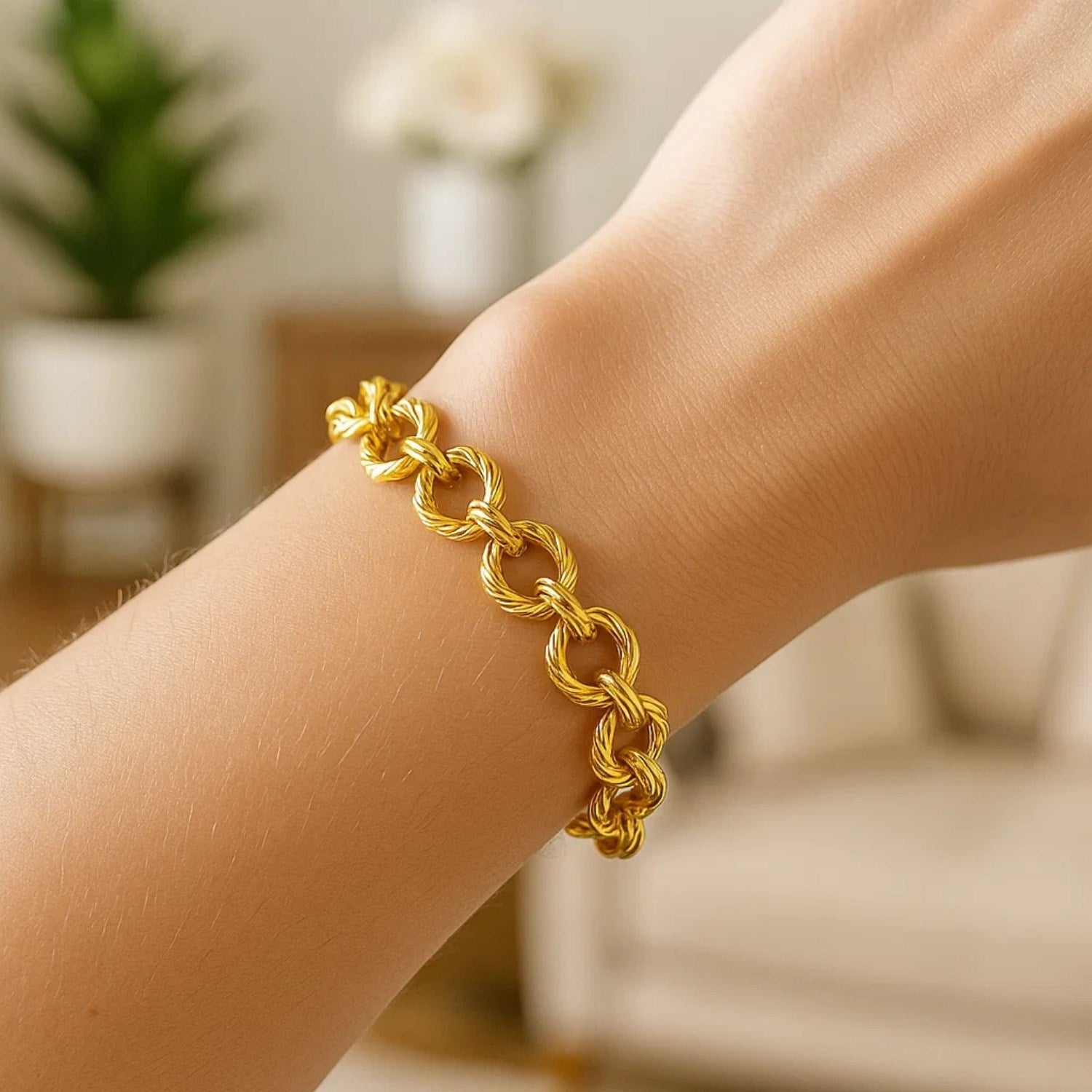A textured oval link bracelet in 14k yellow gold is worn on a wrist.