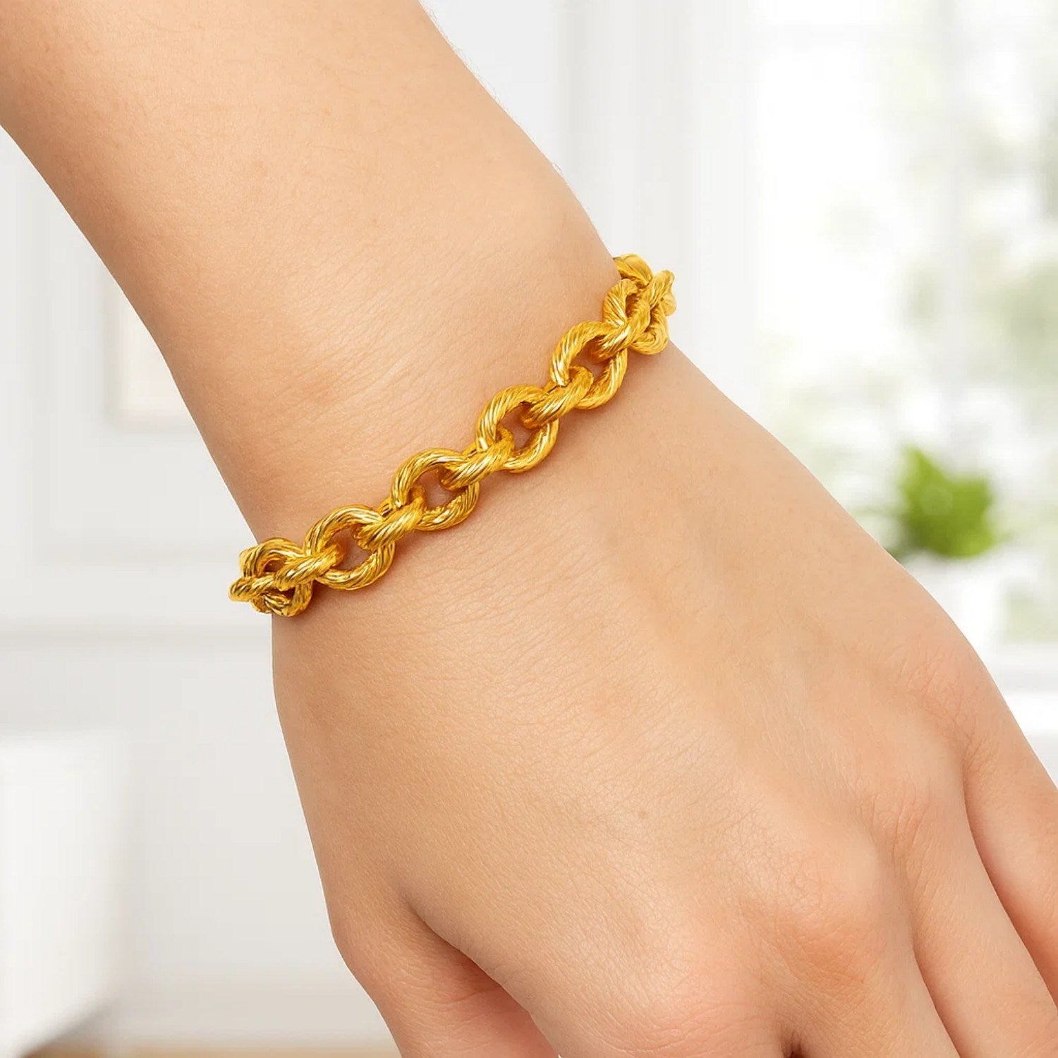 Textured oval link bracelet in 14k yellow gold on a person's wrist.