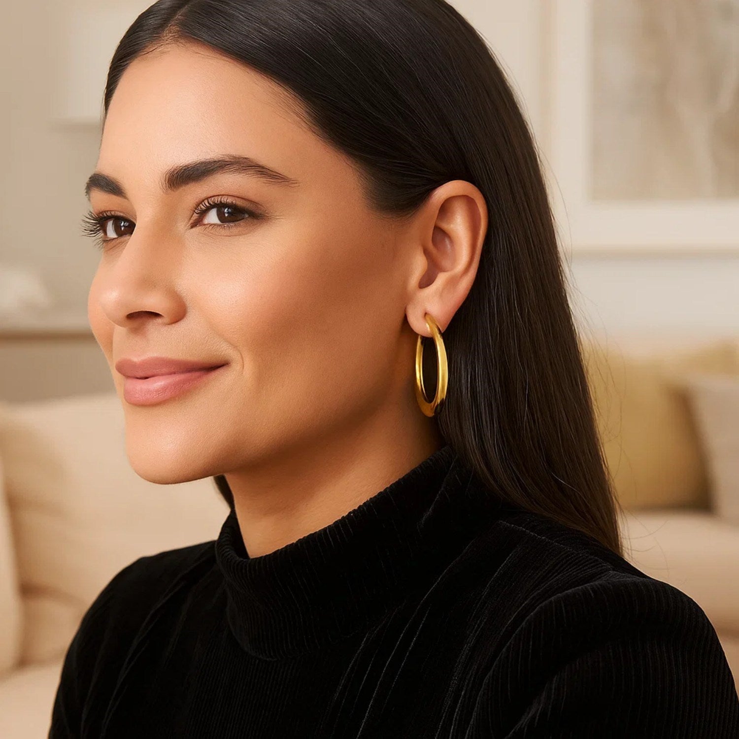 Oval electroform hoop earrings in 14K yellow gold on a woman.