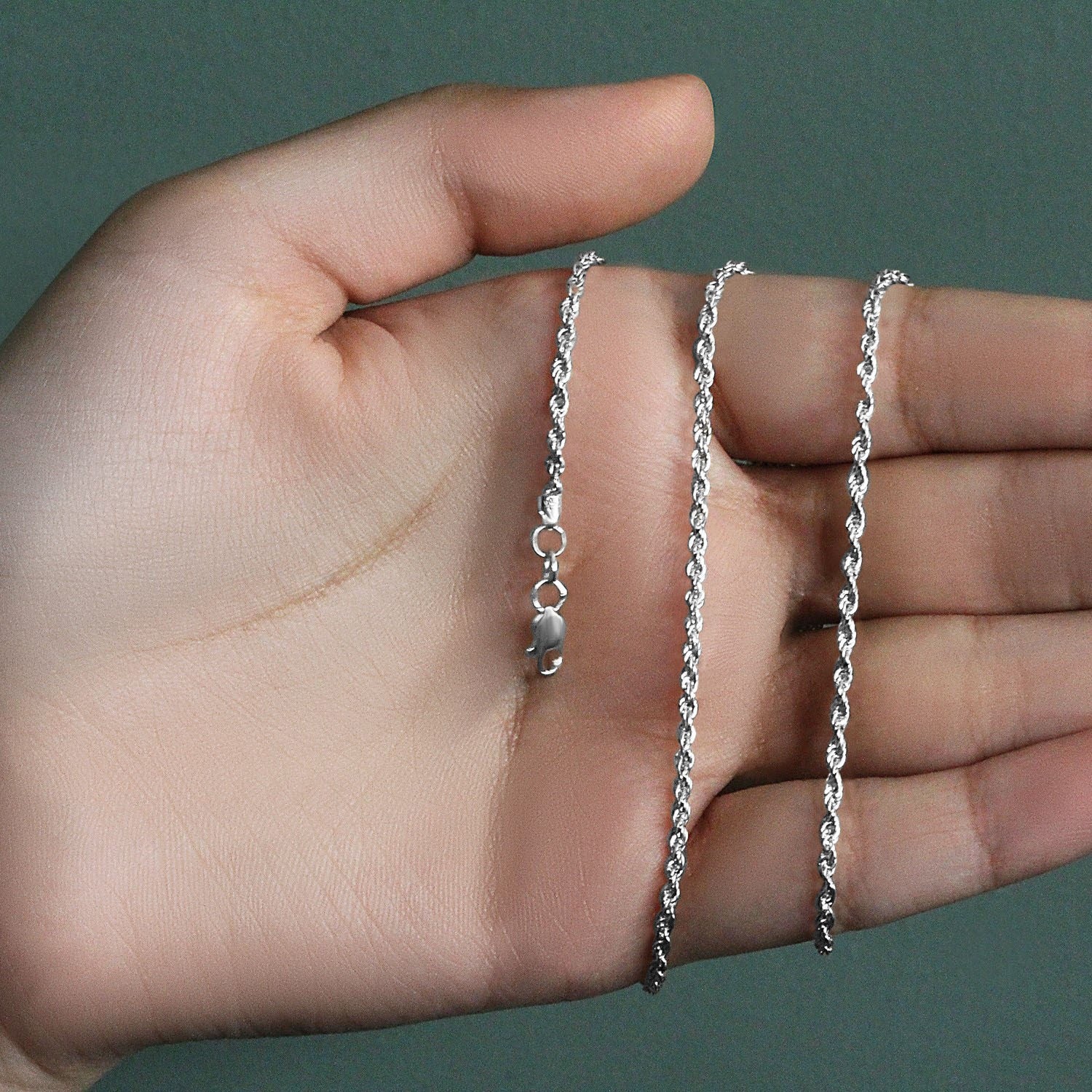 A 14k white gold light rope chain with a lobster clasp is held in an open hand.
