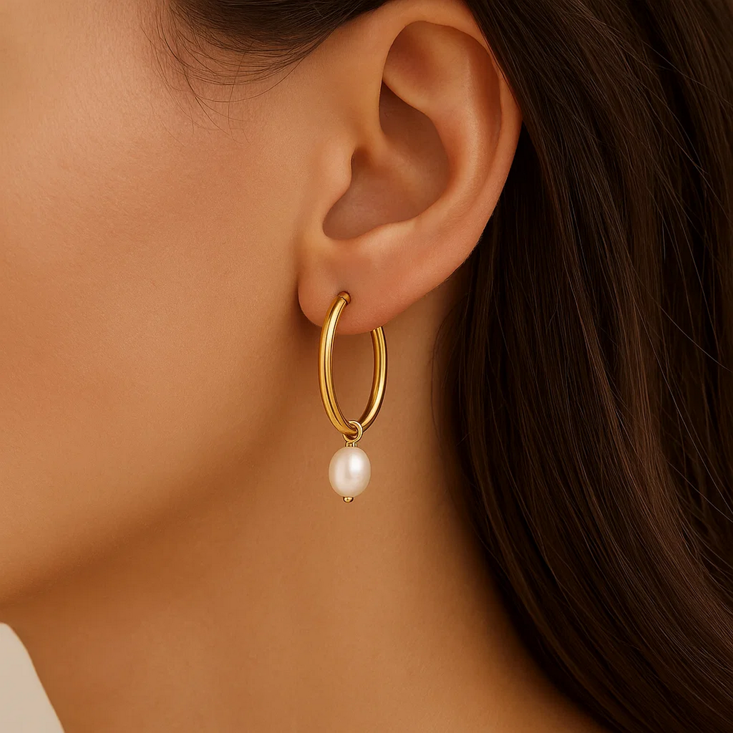 Pearl drop oval earrings in 14K yellow gold on a woman's ear.
