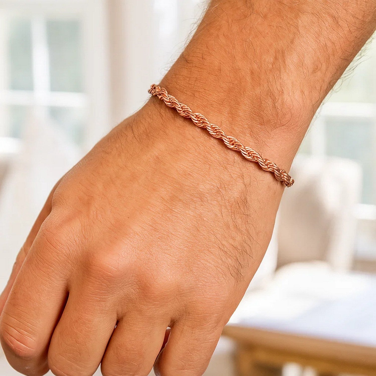 A 14k rose gold solid diamond cut rope bracelet on a person's wrist.