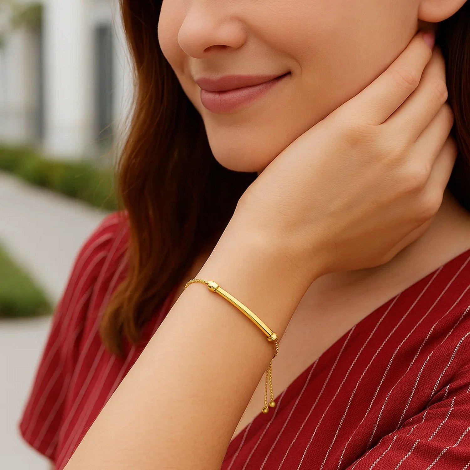 14k yellow gold smooth curved bar and lariat style bracelet on a woman's wrist.