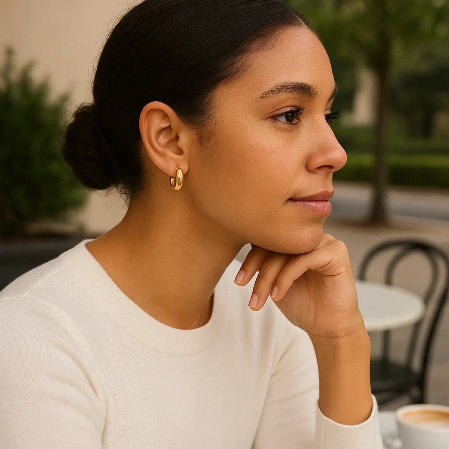 14k yellow gold small puffy hoop earrings on a woman.