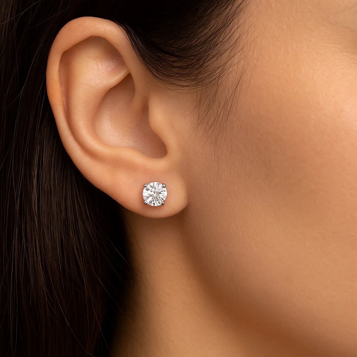 Sterling silver stud earring with a white, faceted cubic zirconia on an ear.