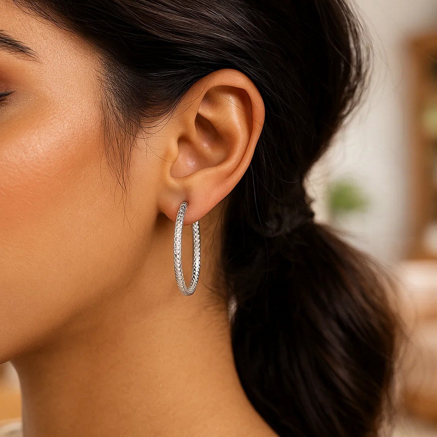 Sterling silver large hoop earrings with a braid texture on a model.