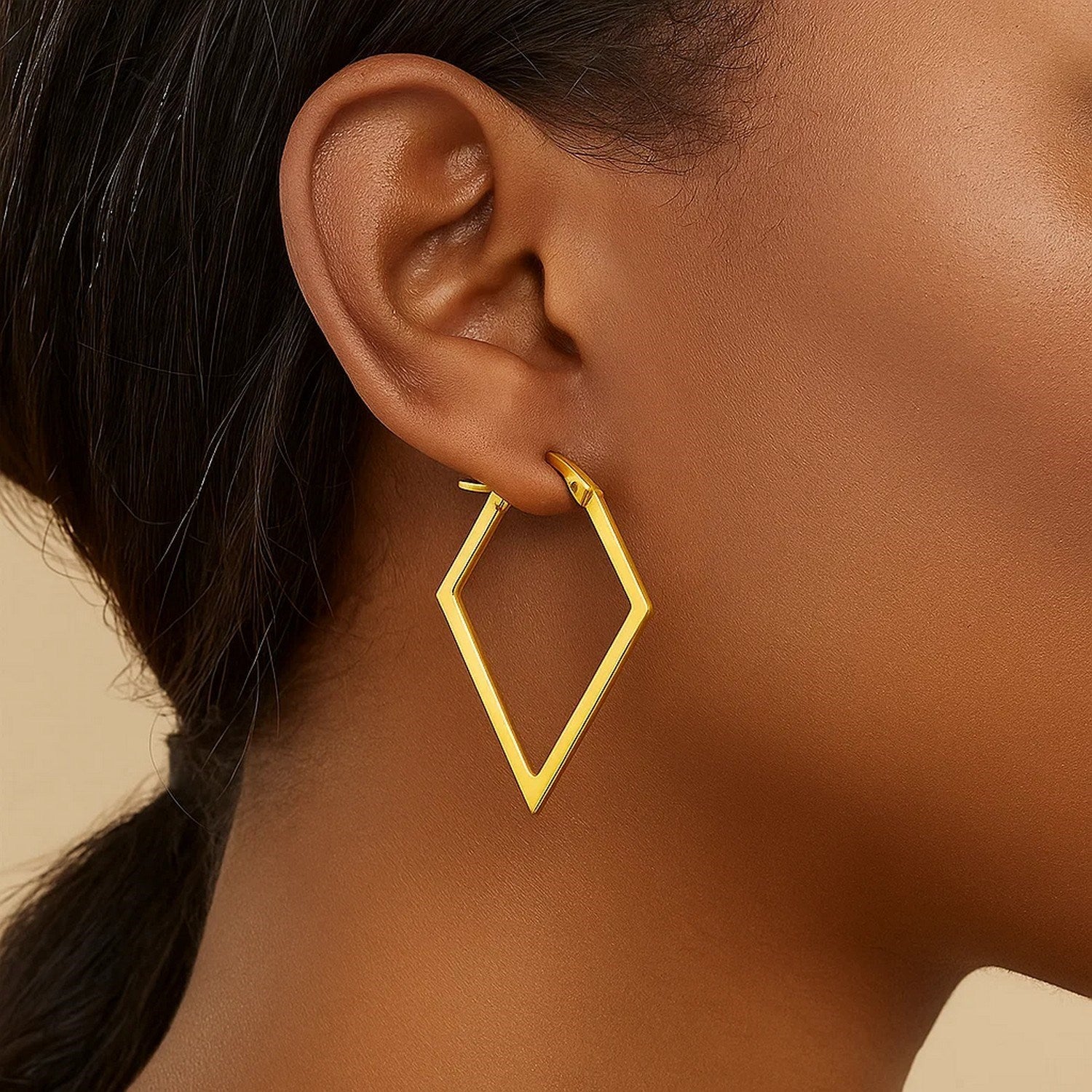 14K yellow gold diamond motif hoop earrings on a person's ear.