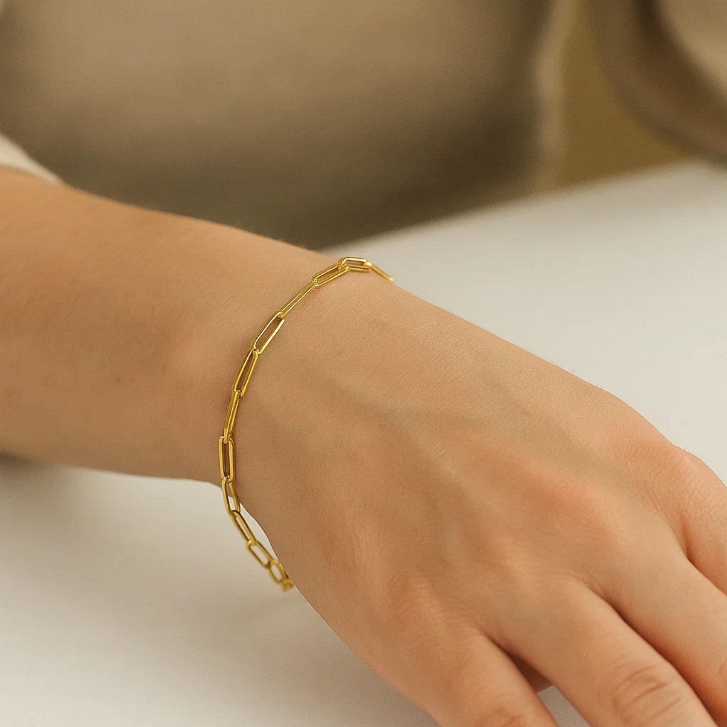 A 10K yellow gold paperclip bracelet with 2.5mm wide links on a person's wrist.