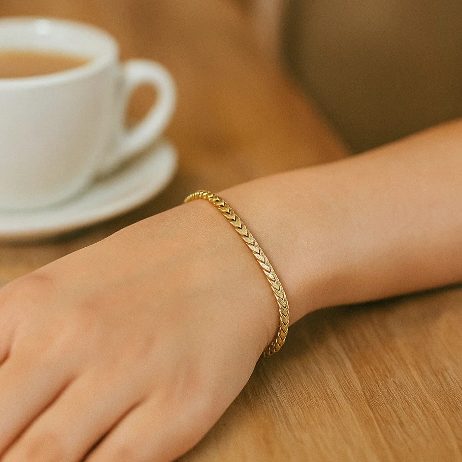 A 14k yellow gold solid diamond cut round franco bracelet on a person's wrist.
