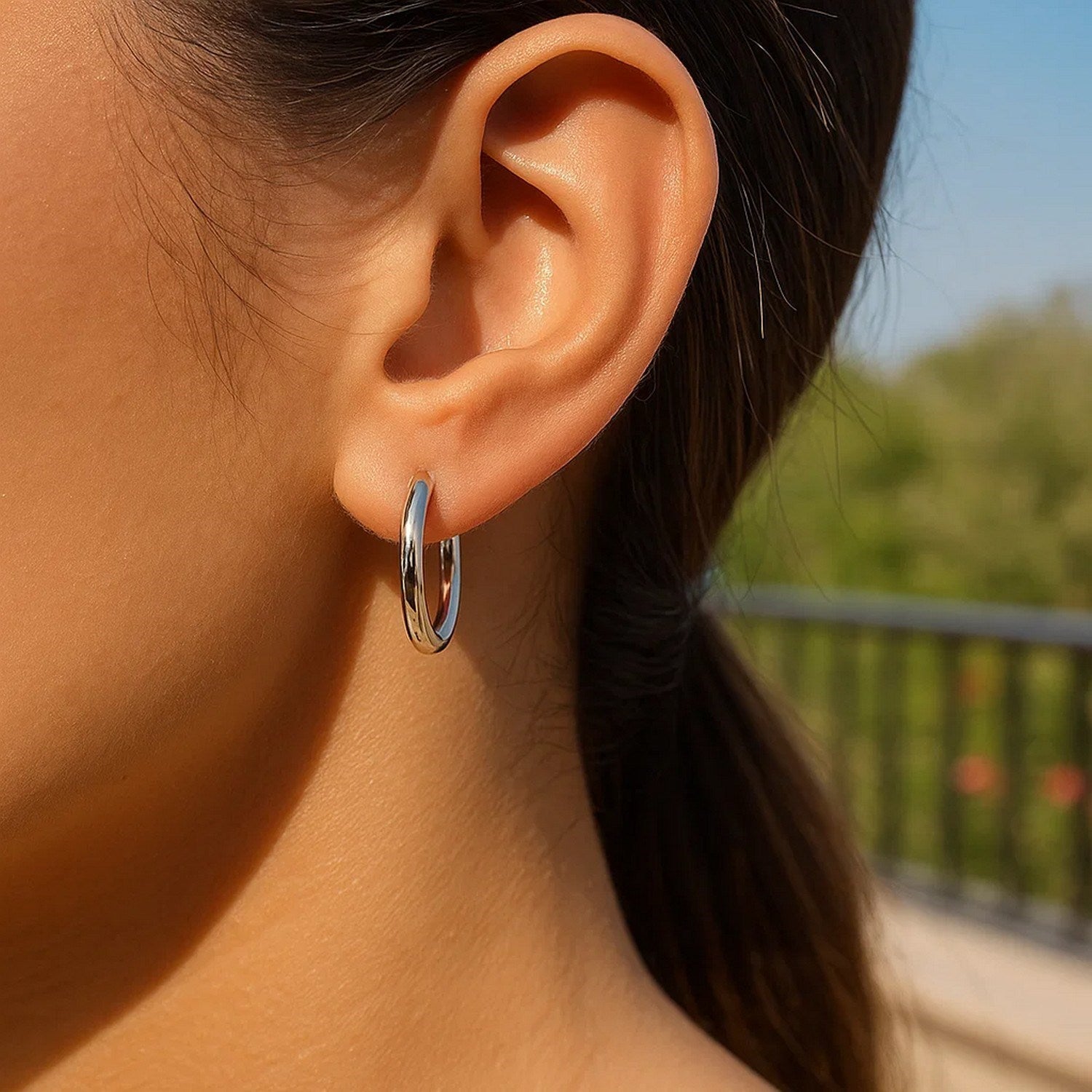 10k white gold polished hoop earrings on a person's ear.