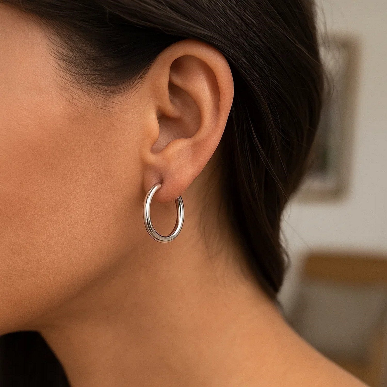 10k white gold polished hoop earrings on a person's ear.